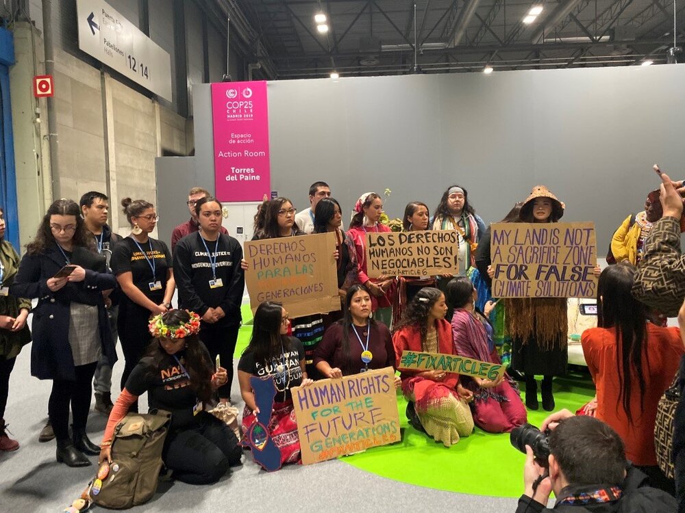 Indigenous youth peacefully protest in the COP25 conference hall, demanding action to protect indigenous people, their land and their rights, and calling out the inadequacy of Article 6, among other things.
