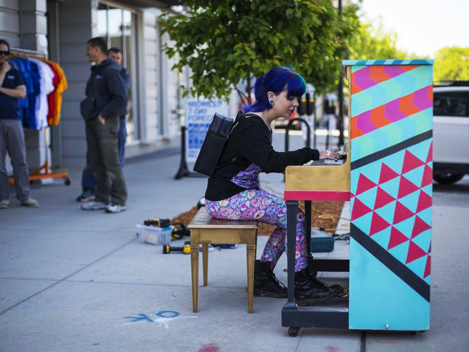 On her way to work in the East Village, Zoe Fey of Des Moines plays a piano being installed in front of RAYGUN for the City Sounds: Des Moines Public Piano Project. Photo by Rodney White/The Register