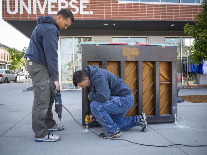 Andre Drost, left, and Vasile Zama, right, install a pianl in front of RAYGUN for the City Sounds: Des Moines Public Piano Project. Thursday May 19, 2016. Photo by Rodney White / The Register.