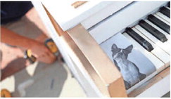 A photo of a dog decorates the keyboard as Andre Drost with ACR Construction anchors the piano to the ground.