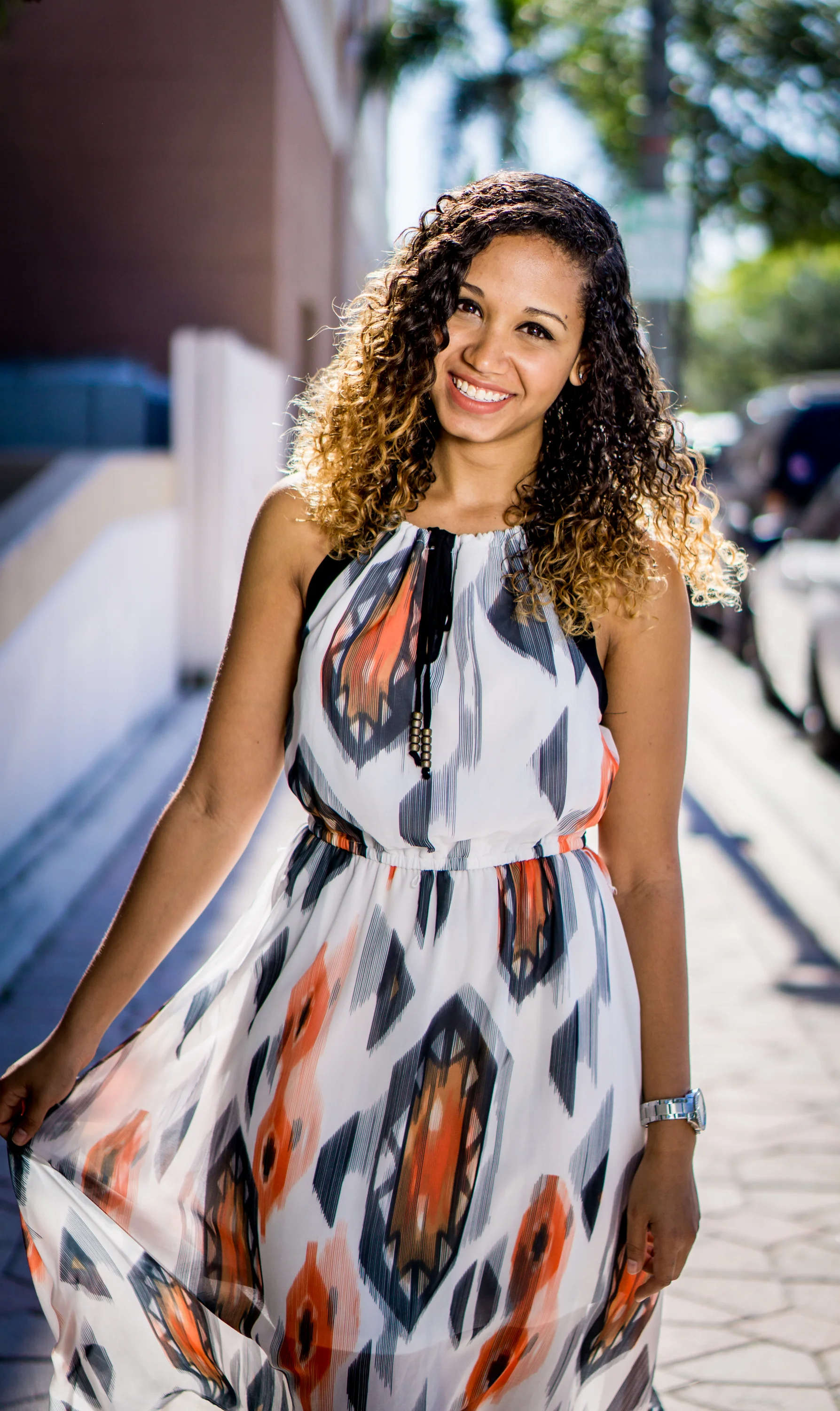 Smiling woman in patterned dress on a sunny street