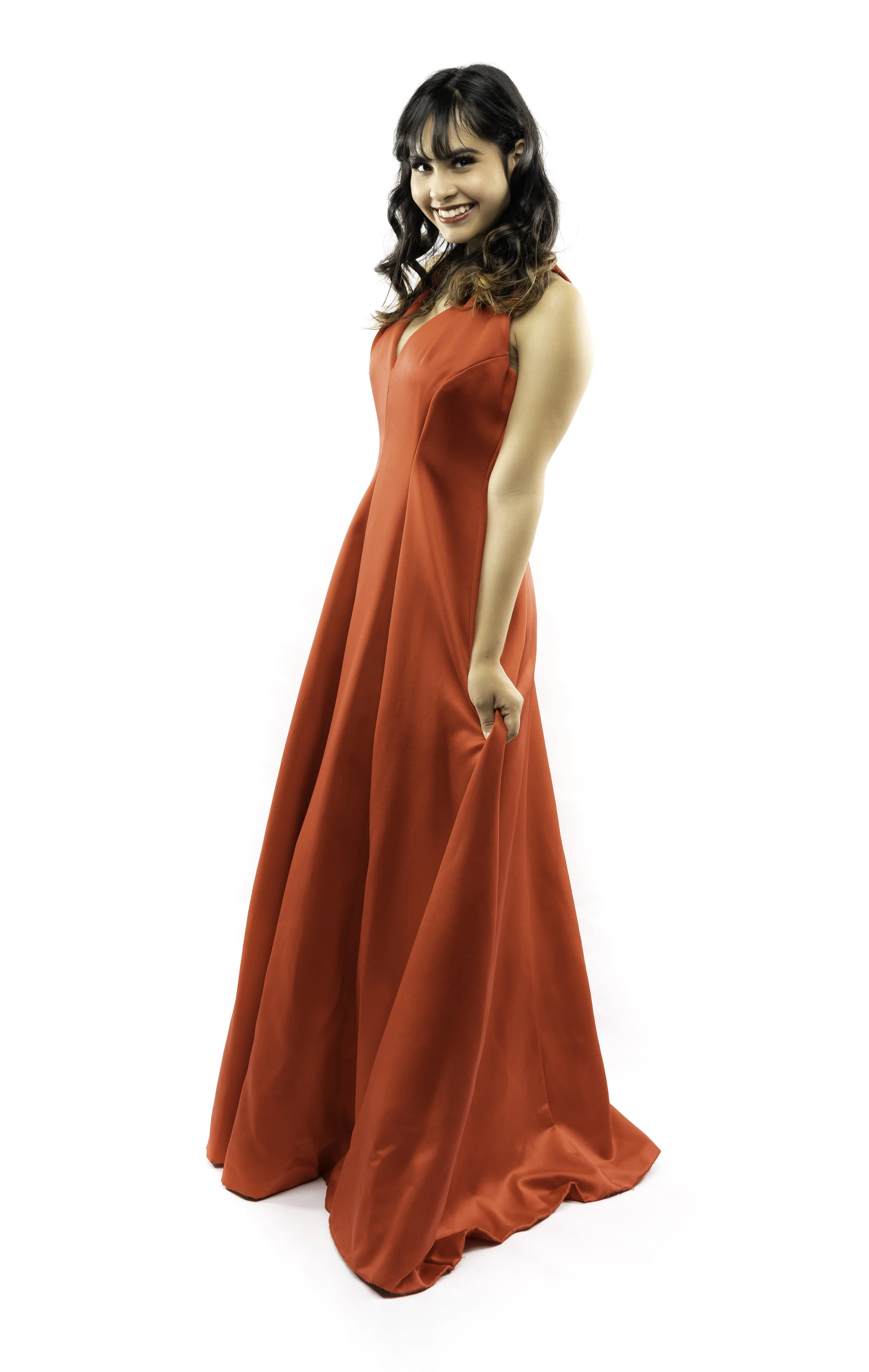 Woman wearing a long, red evening gown, smiling, against a white background.