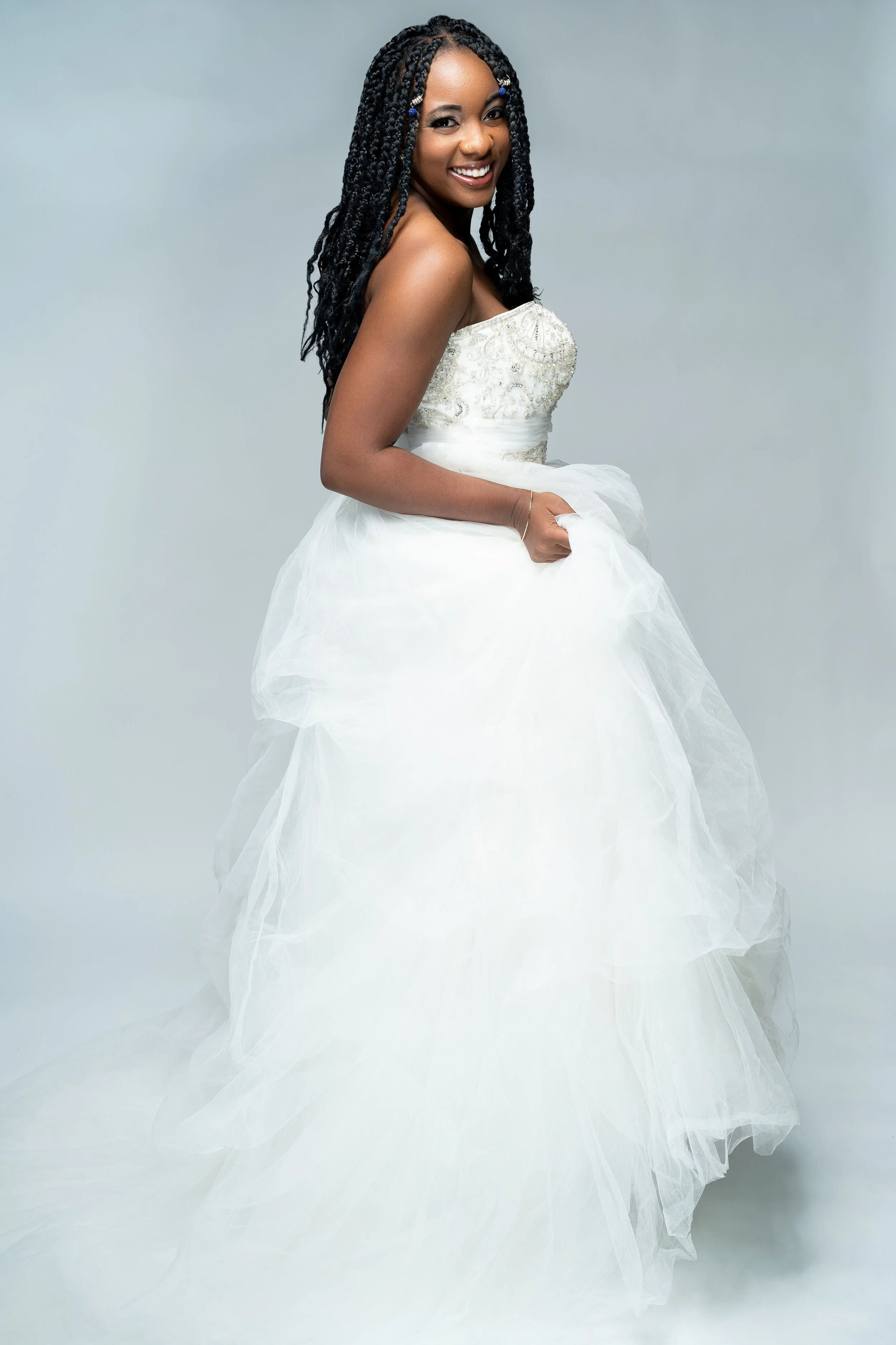 A woman in a wedding dress smiling against a neutral backdrop.