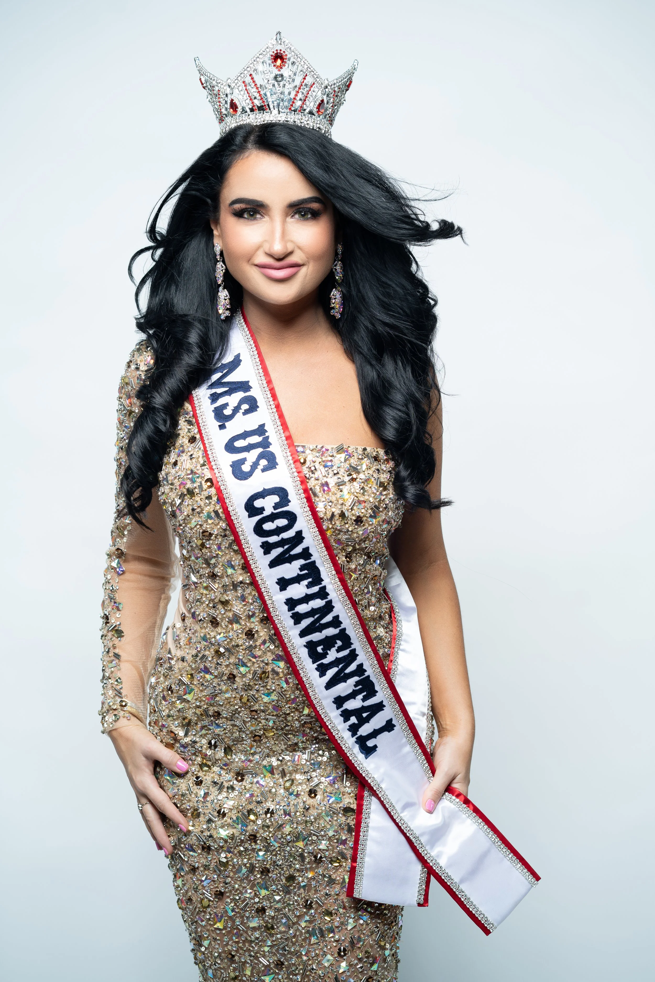 Woman wearing a crown and sash labeled "MS. US CONTINENTAL" in a sparkly dress.
