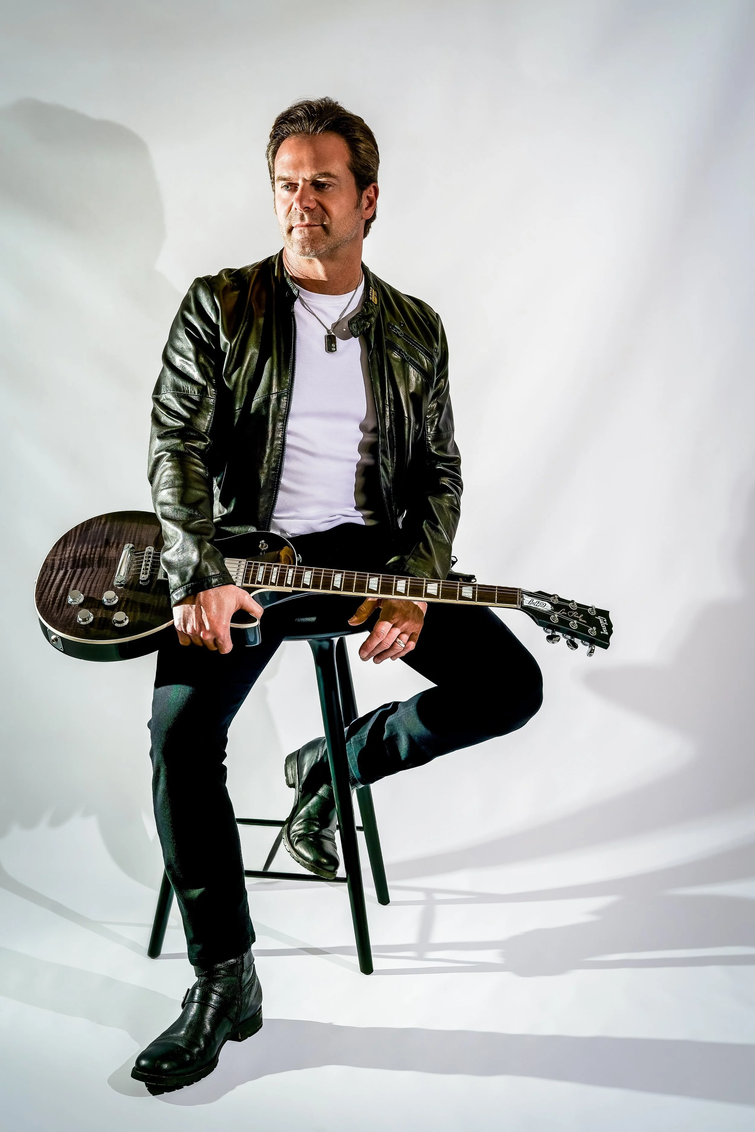 Man sitting on a stool with a guitar