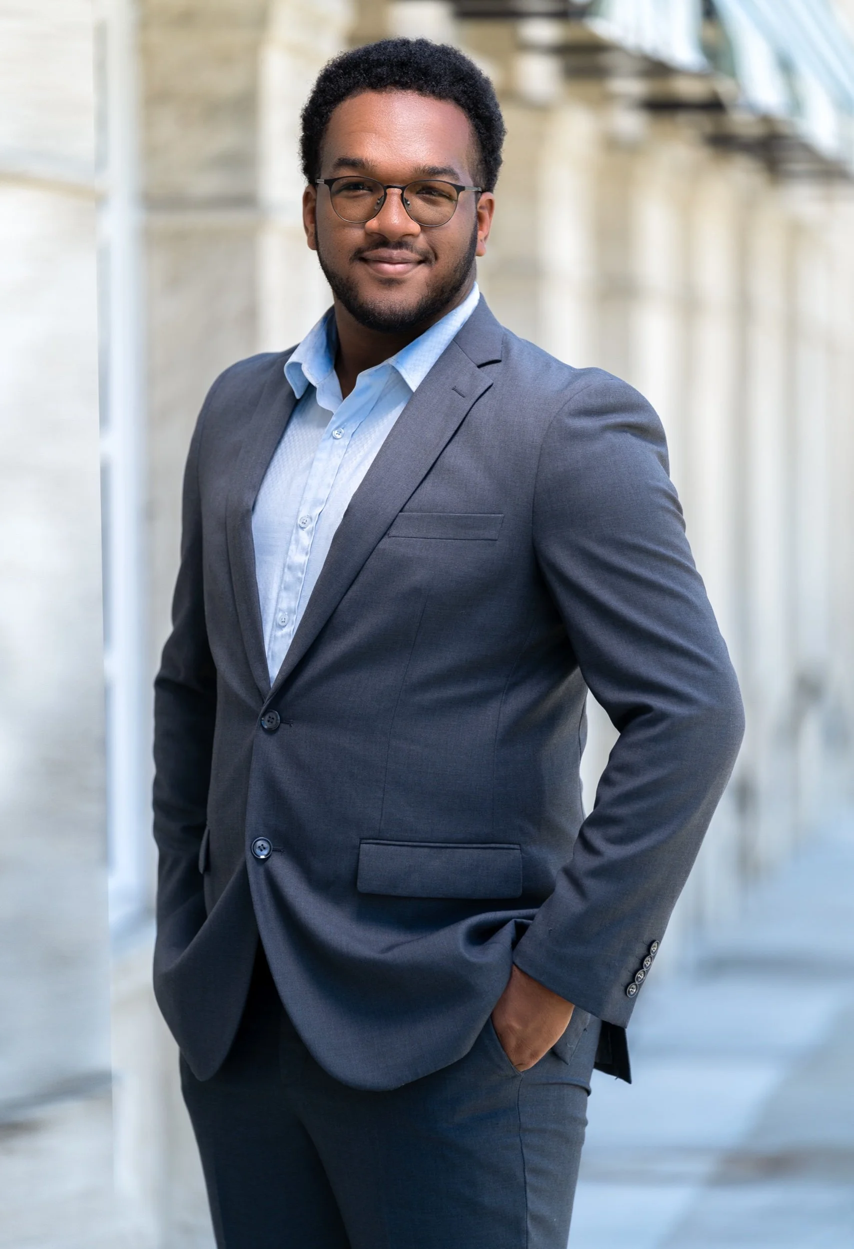 Confident man in a gray suit with glasses.