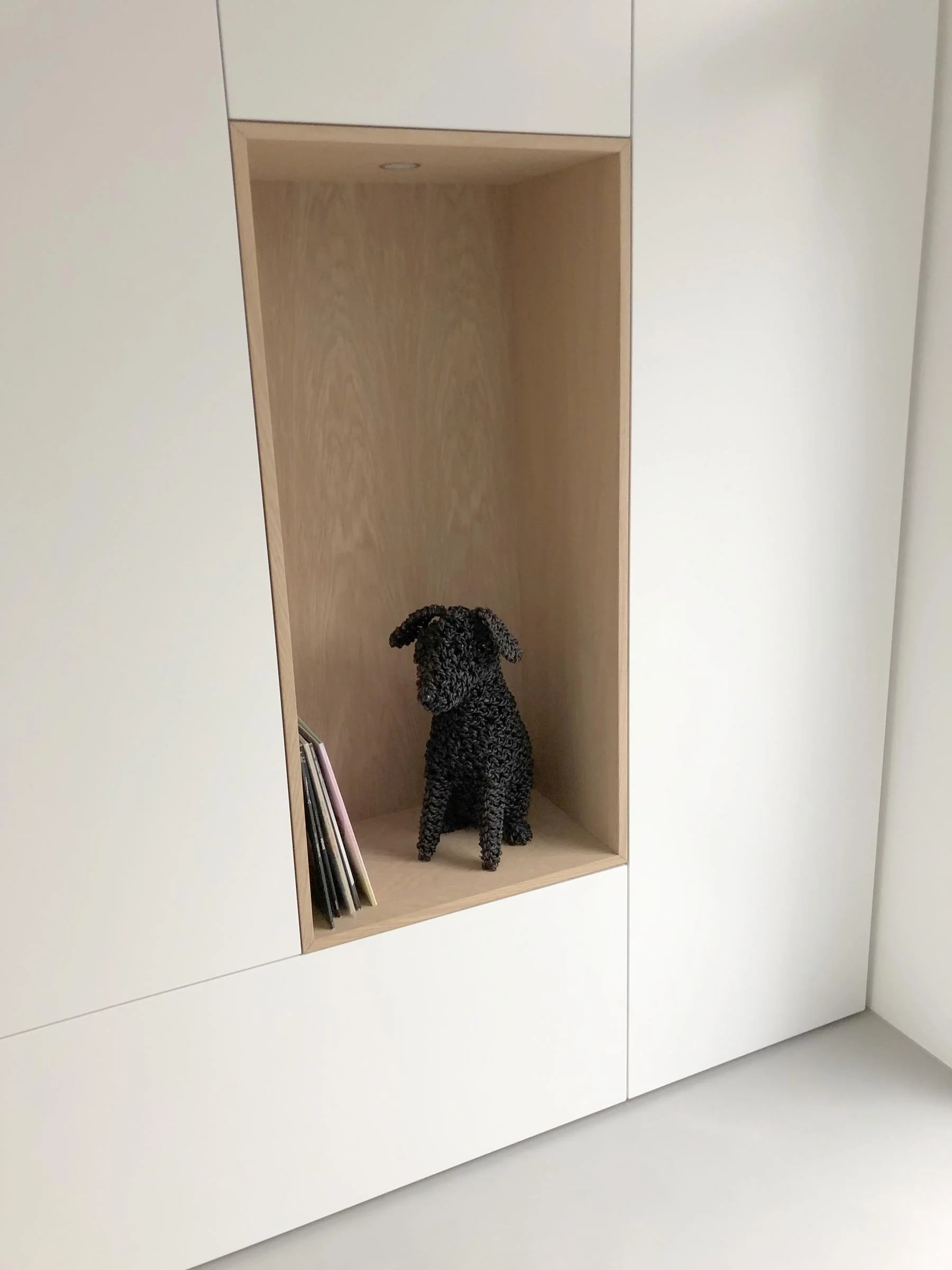 Detail van een witte kastenwand op maat met open vak in eiken fineer