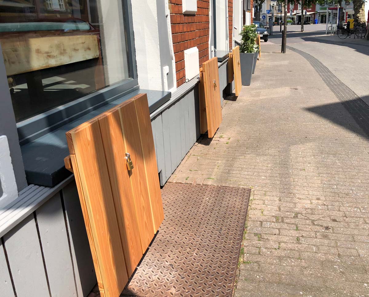 Een rij outdoor klaptafels voor een bar ingeklapt en met een hangslot afgesloten.