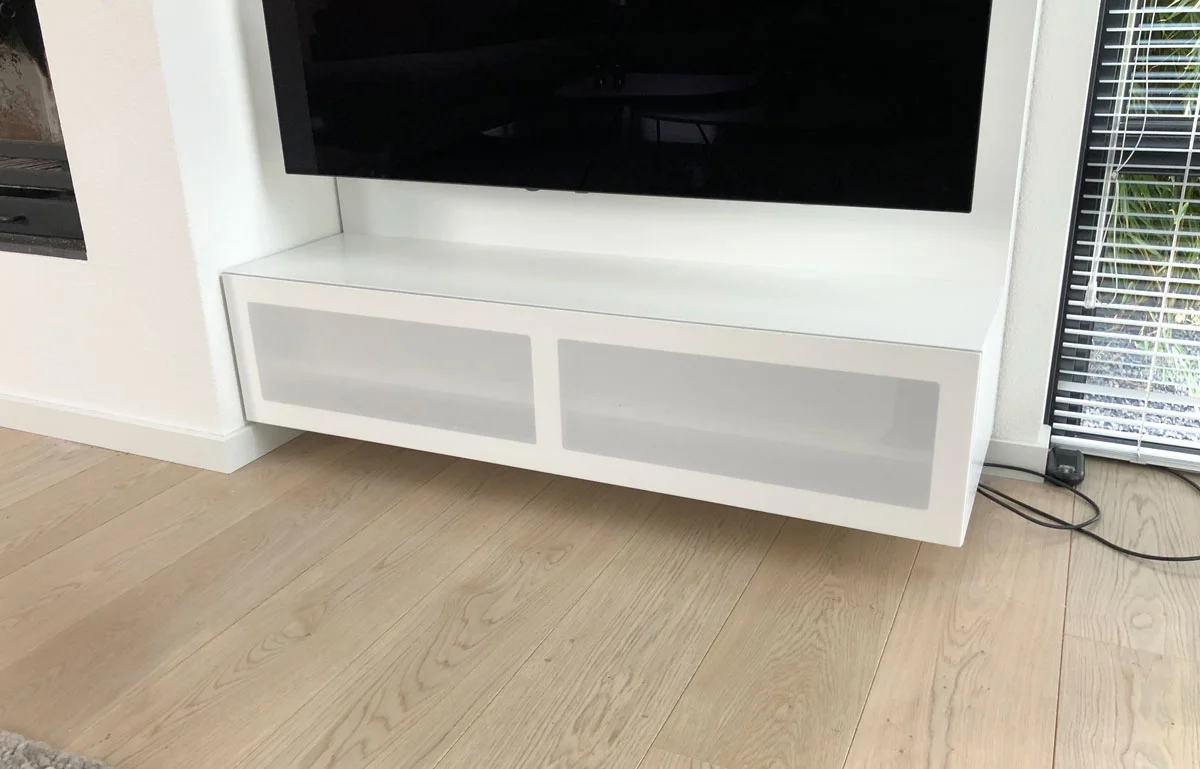 Afbeelding van een minimalistische gesloten luidsprekerklep in een wit TV meubel.