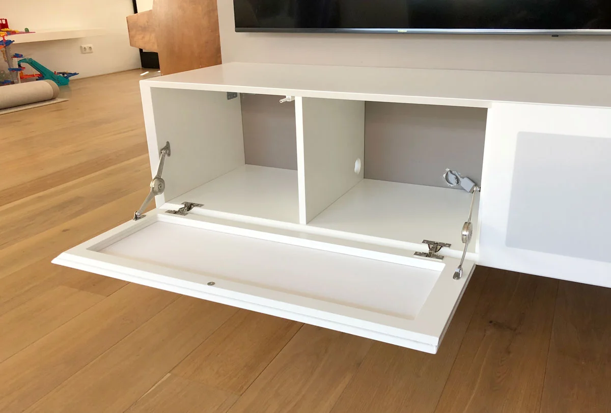 Afbeelding van een geopende luidsprekerklep in een wit design TV meubel.
