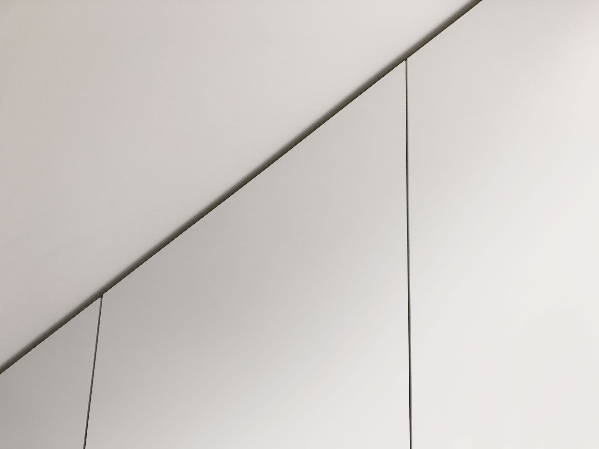 Detail van schaduwvoeg boven witte kastenwand op maat onder schuin plafond