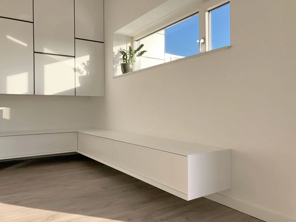 Wit zwevend hoek-TV-meubel op maat onder hoge wandkasten