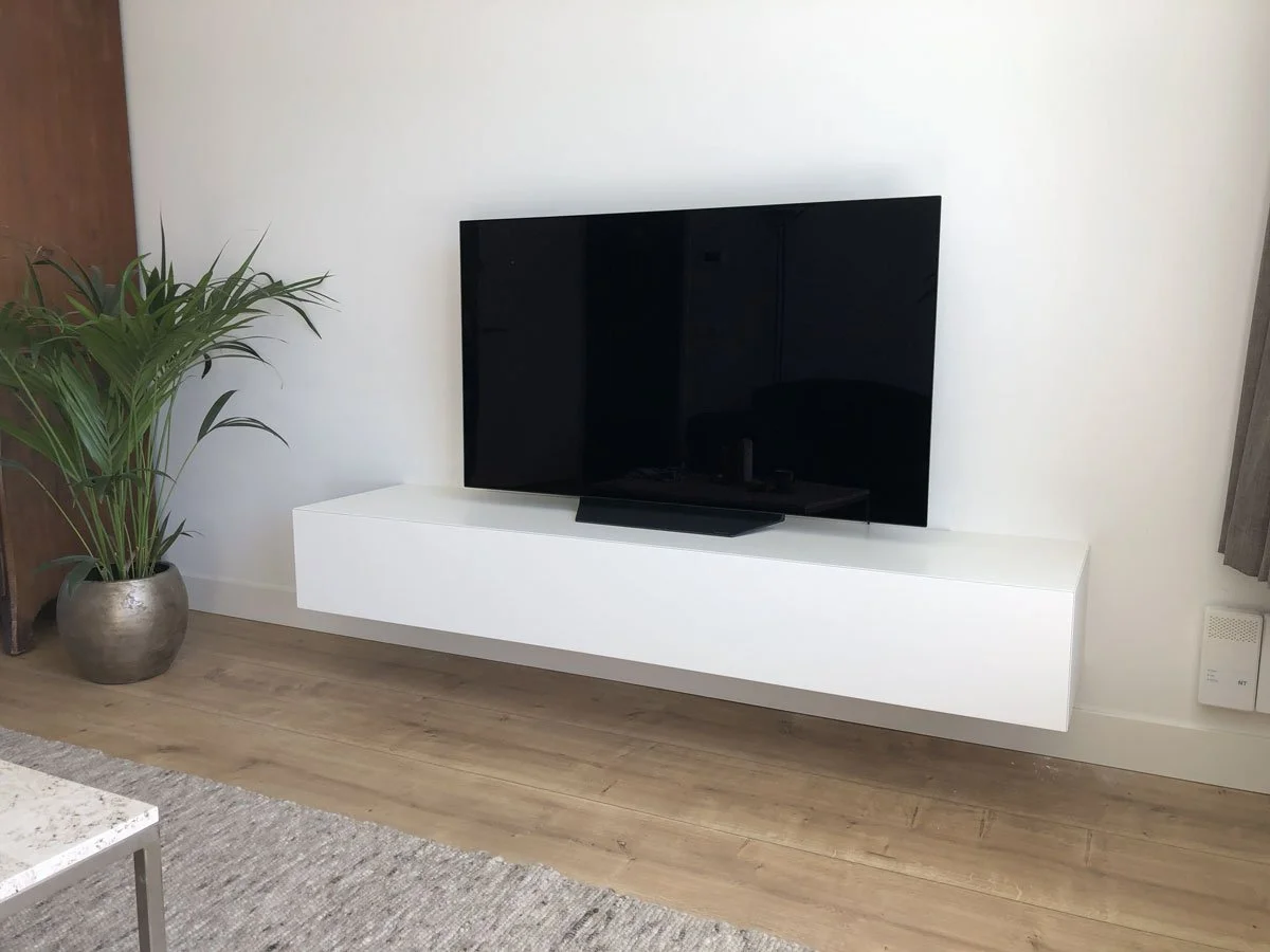 Strak gemonteerd wit zwevend TV-meubel op maat onder wand-TV