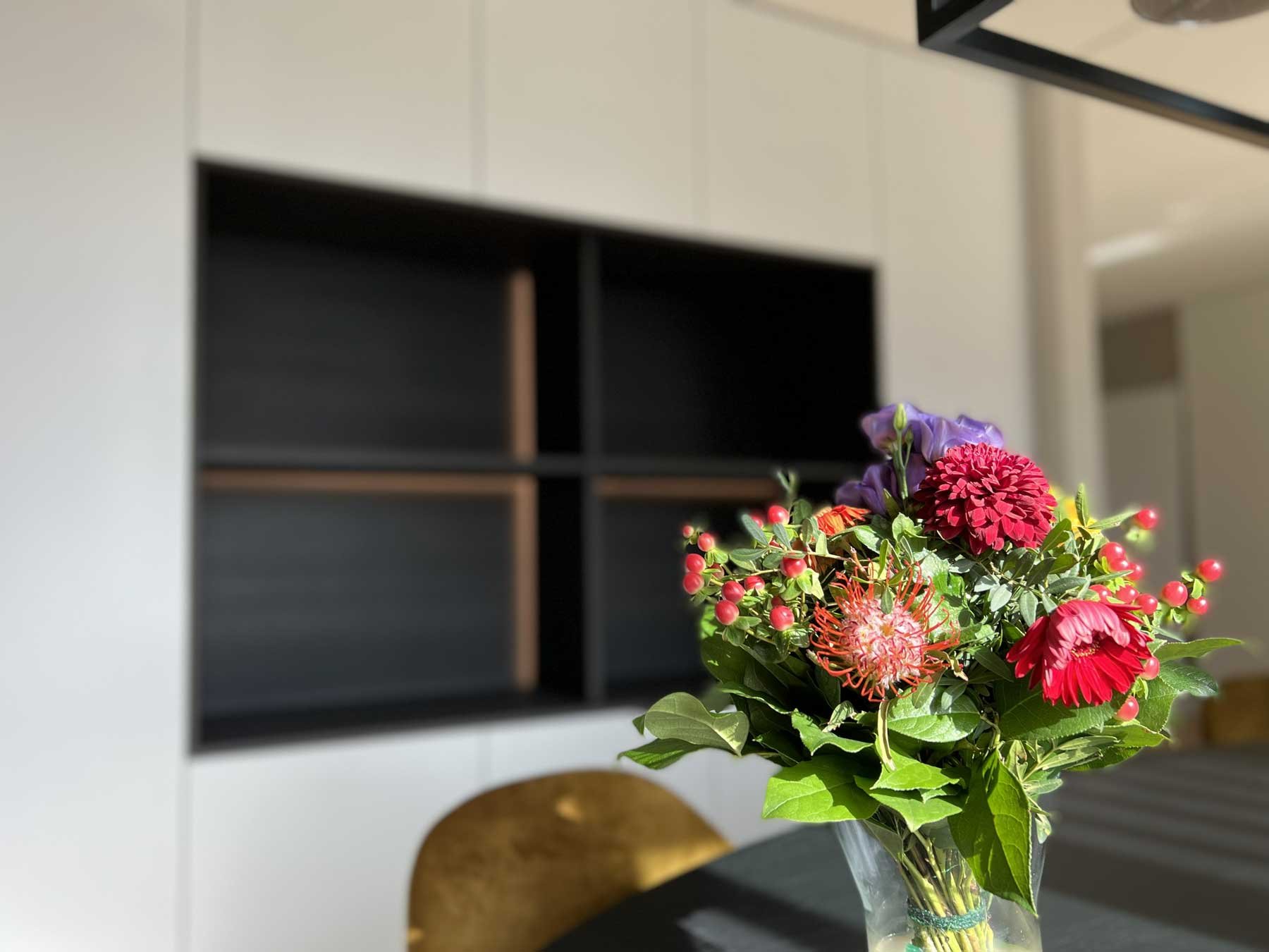 Sfeerbeeld met bloemen in vaas en een kastenwand op maat op de achtergrond