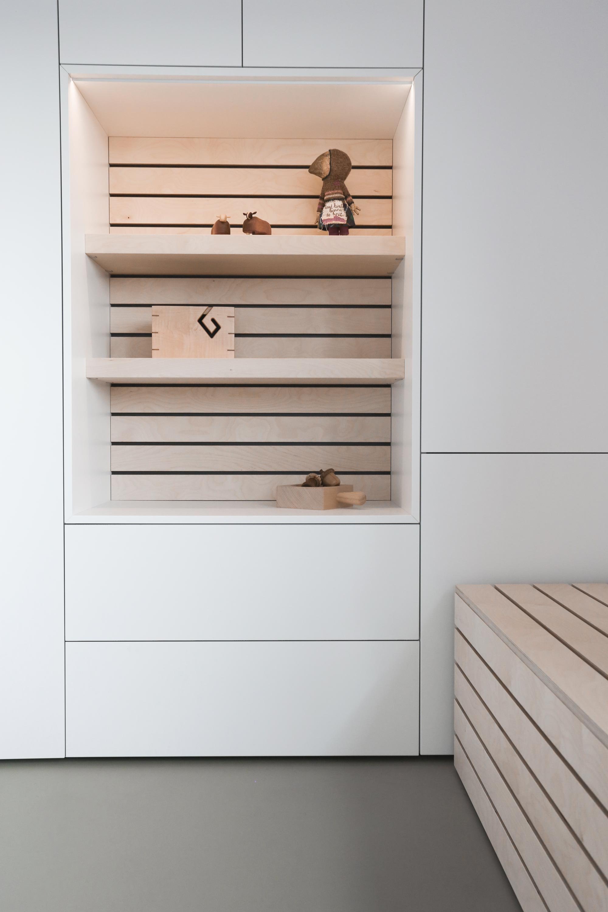 Detail van open vak met LED verlichting in gesloten kastenwand, met houten latten als achterwand