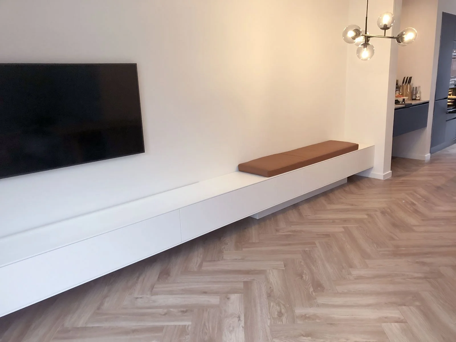 Lang wit TV-meubel op maat met zitkussen en doorlopende lijn