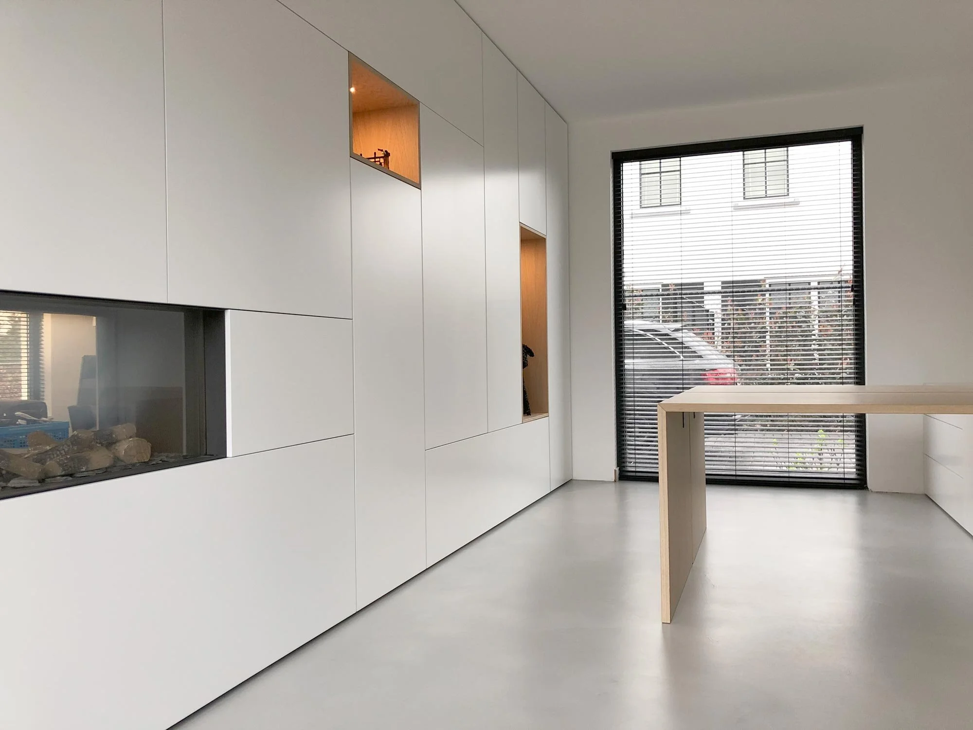 Witte inbouw kastenwand op maat met geïntegreerde haard en open vakken in eiken fineer