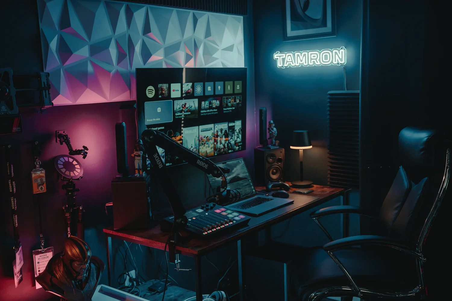 Wide view of Pittsburgh photography and podcast studio with Tamron sign, RGB lighting, RODE microphone, and laptop