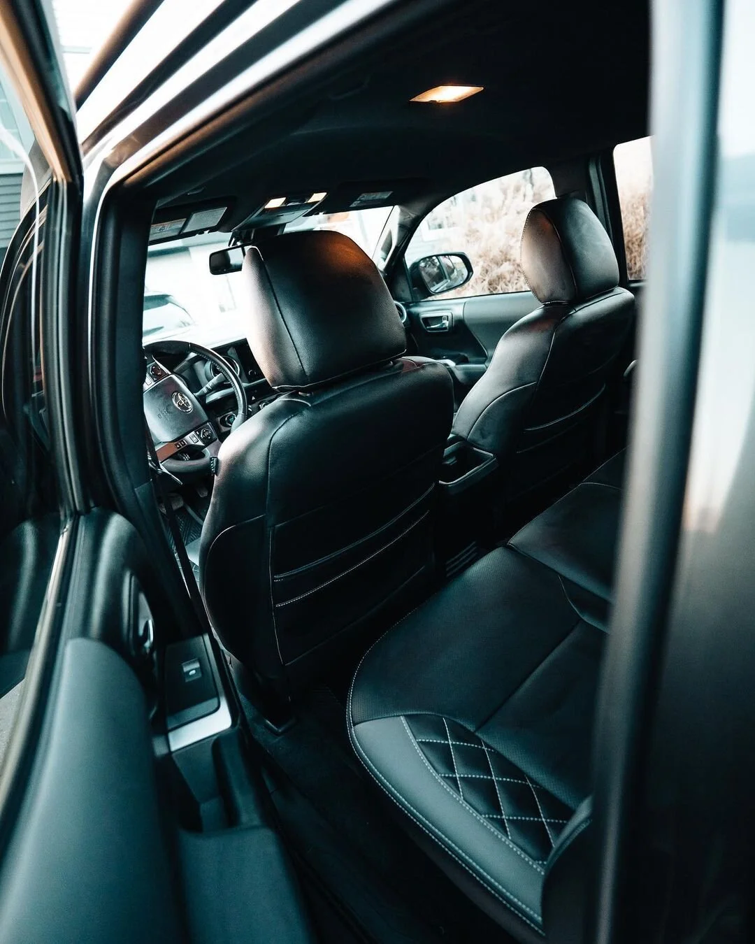 Interior view of the 2019 Toyota Tacoma TRD Sport build showing custom black leather seats with stitched details, rear cabin space, and upgraded daily-use interior photographed by Ian Jones for ISJDESIGNS.