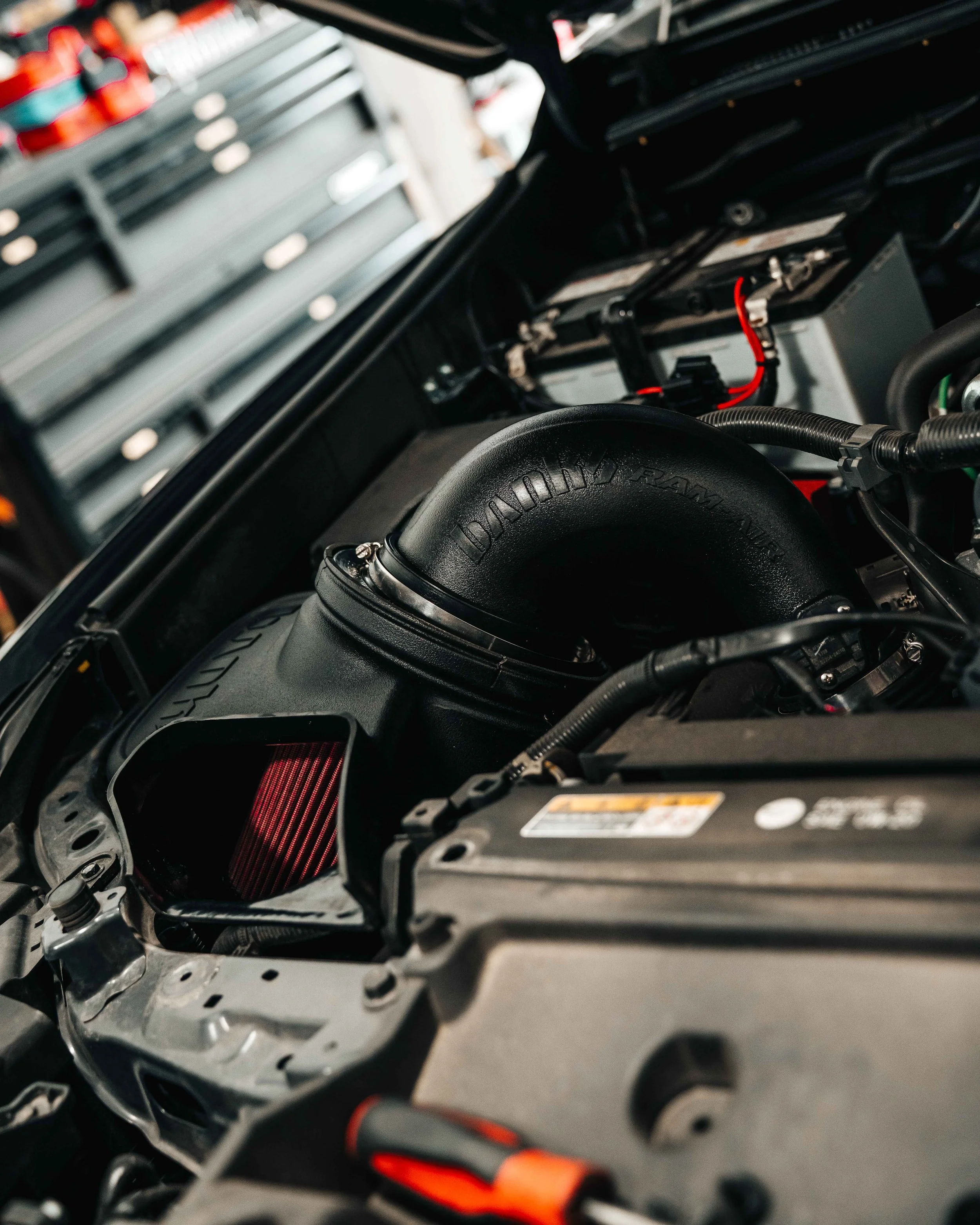 Banks Ram-Air intake installed in the engine bay of a 2025 Toyota 4Runner TRD Sport, showing the molded Ram-Air housing, red oiled filter inside the enclosed airbox, and factory wiring and battery routing around the finished install.