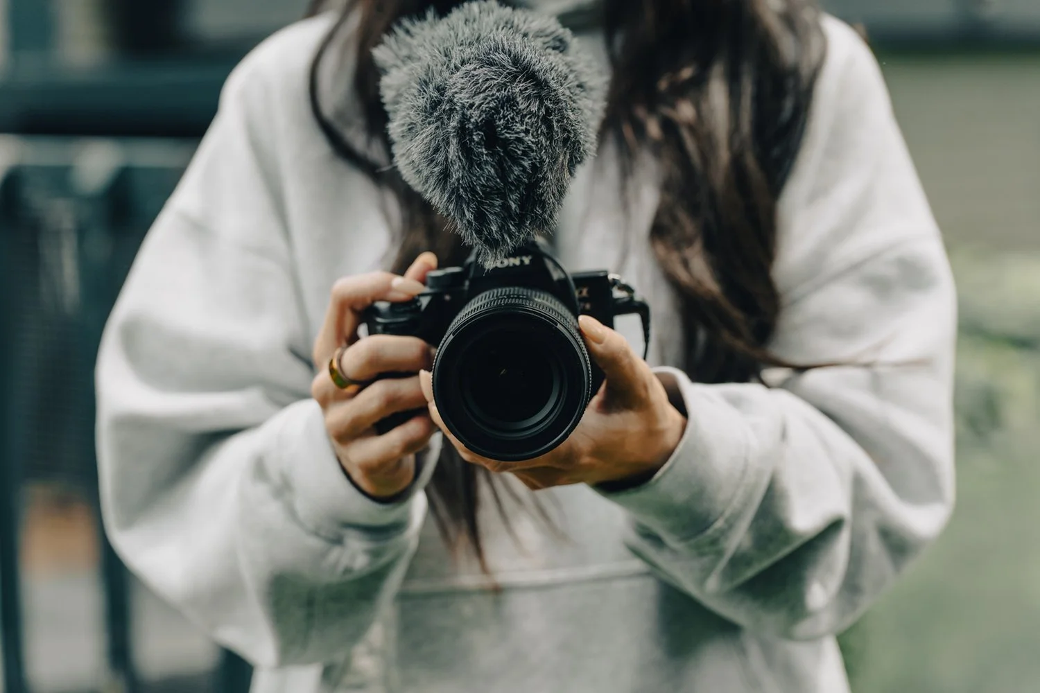 Close-up of a content creator holding a Sony mirrorless camera with an external microphone, showcasing modern gear setup for photography and video production in 2025. Ian Jones Pittsburgh Photography | ISJDESIGNS.