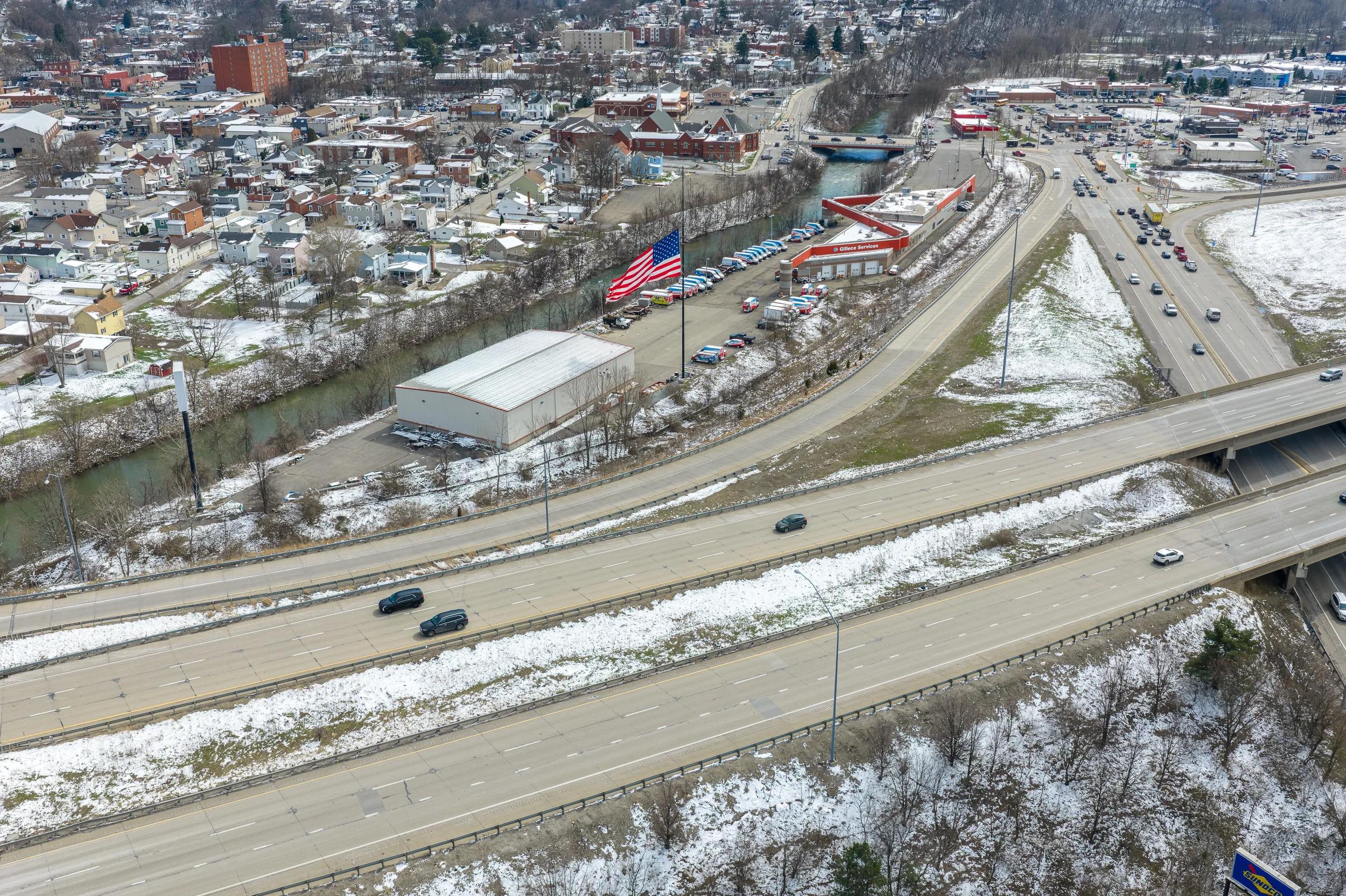 Pittsburgh aerial drone photography showing a highway corridor, neighborhood, commercial buildings, and local traffic patterns in Western PA.