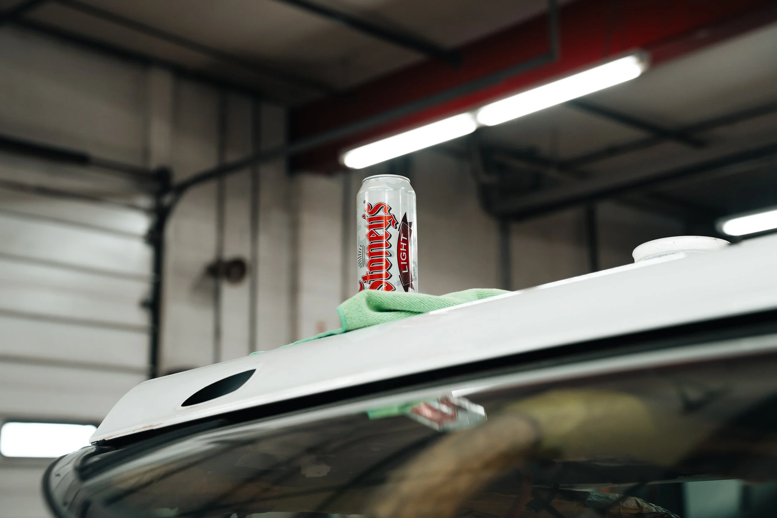 Stoney's Light beer can on a white truck roof at an automotive shop