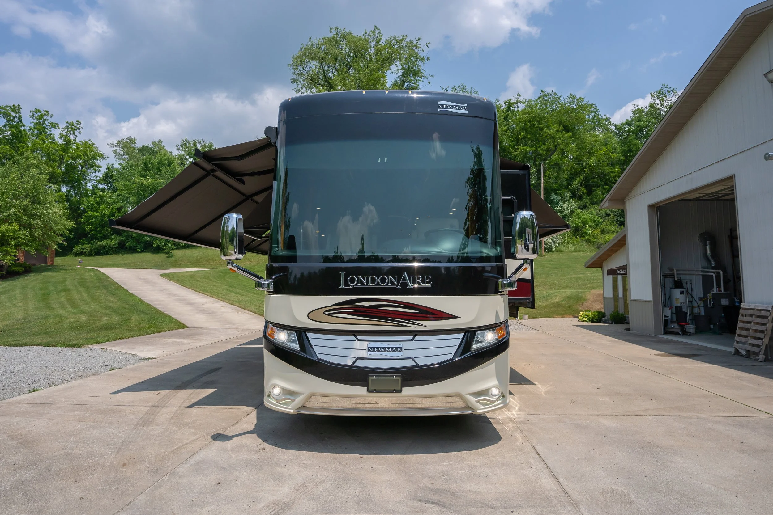 Front view of Newmar London Aire Class A motorcoach with awnings extended, LondonAire script badging and Newmar grille emblem visible, champagne and black two-tone exterior, photographed by Pittsburgh commercial photographer Ian Jones
