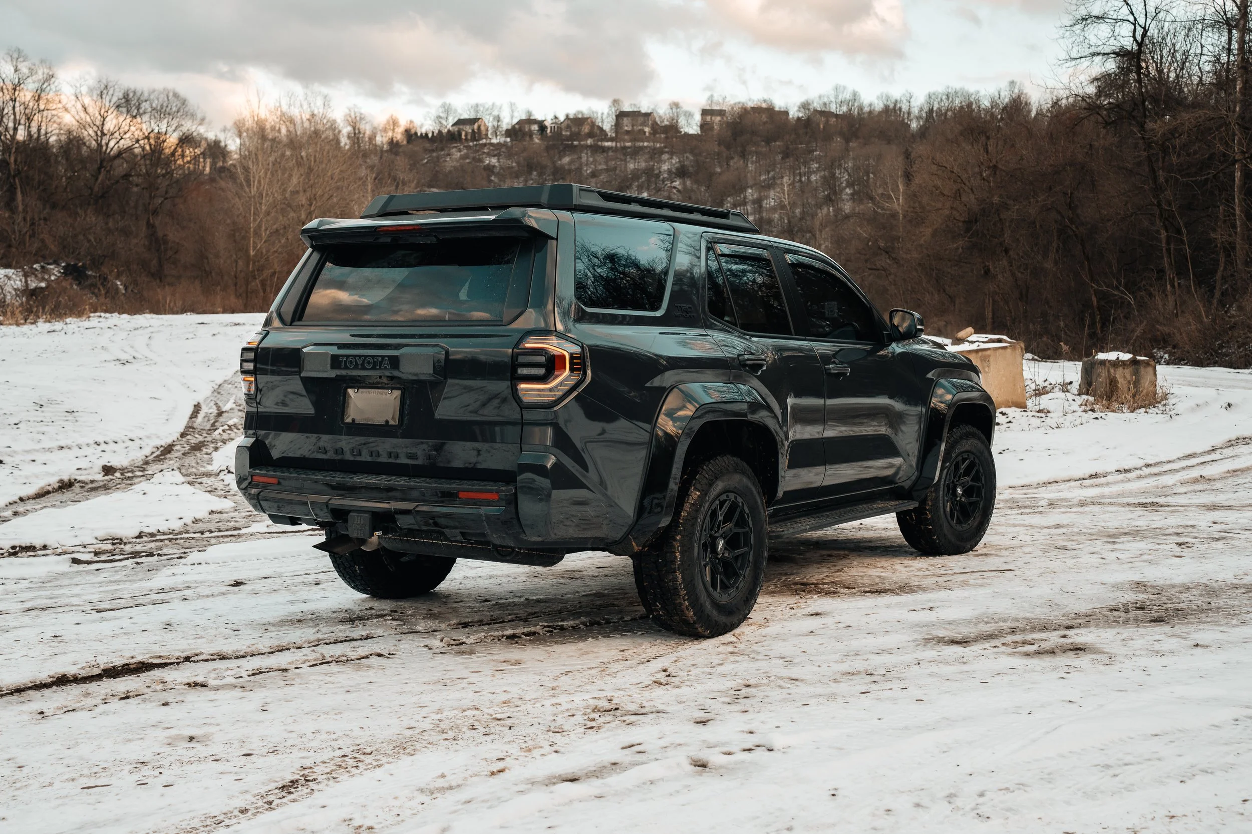 Rear three-quarter view of a 2025 Toyota 4Runner TRD Sport on a snowy, muddy lot at sunset, showing aftermarket wheels and all-terrain tires — taken by Ian Jones of ISJDESIGNS in Pittsburgh, PA.