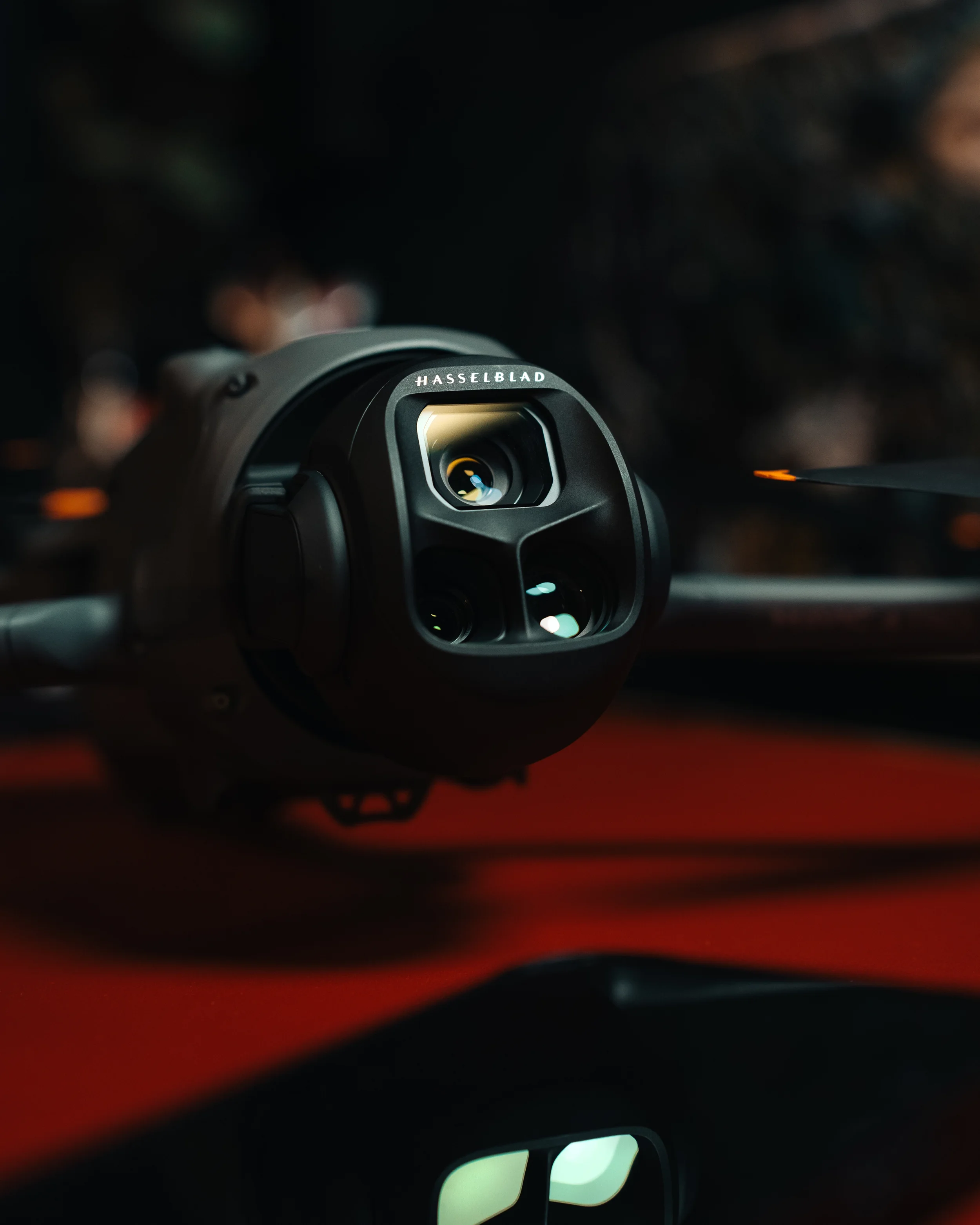 Close-up product photo of the DJI Mavic 4 Pro Hasselblad camera gimbal against a dark background with red surface, shot by Pittsburgh commercial photographer Ian Jones