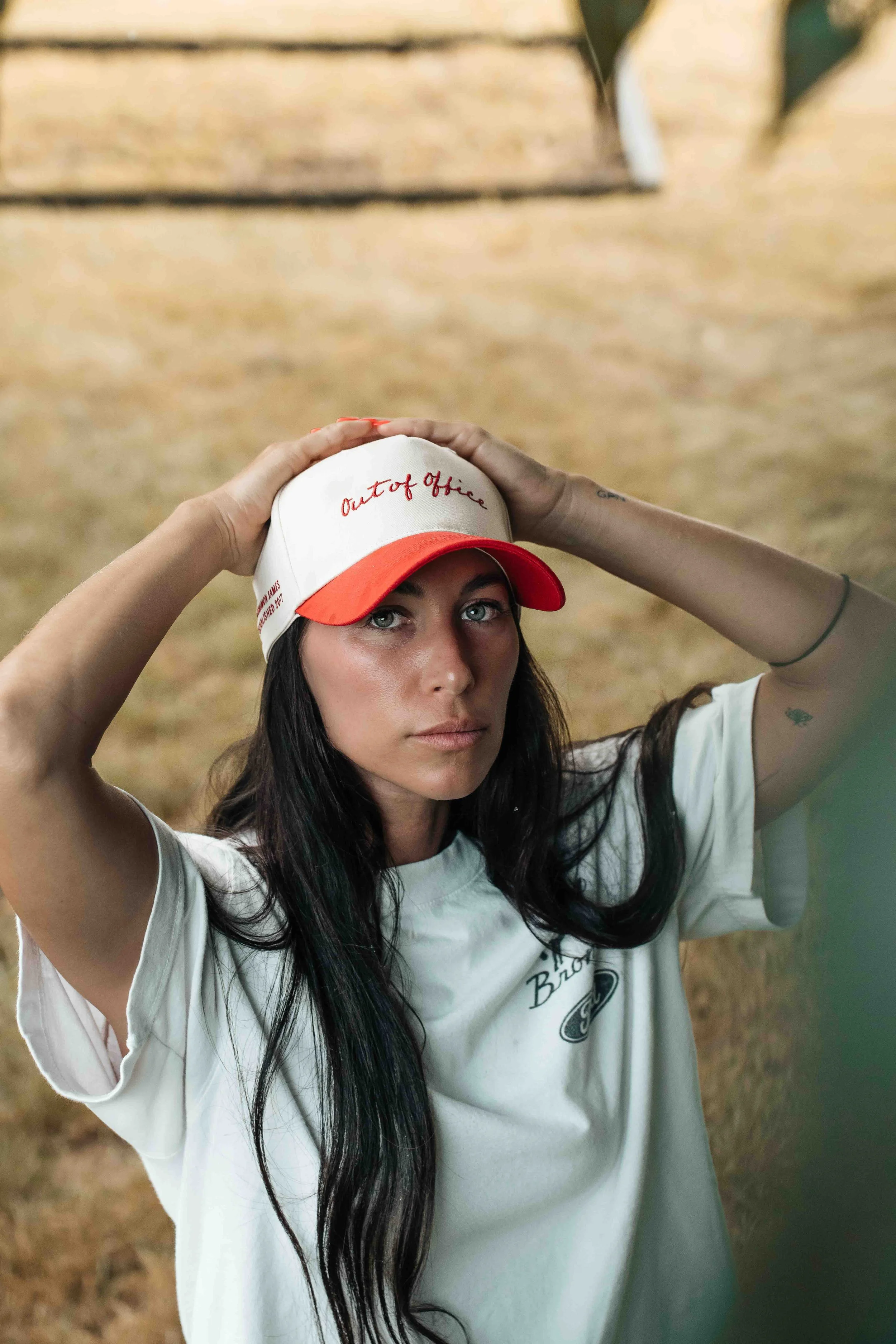 Out of Office trucker hat photographed on a model in a dry field for an apparel lifestyle campaign