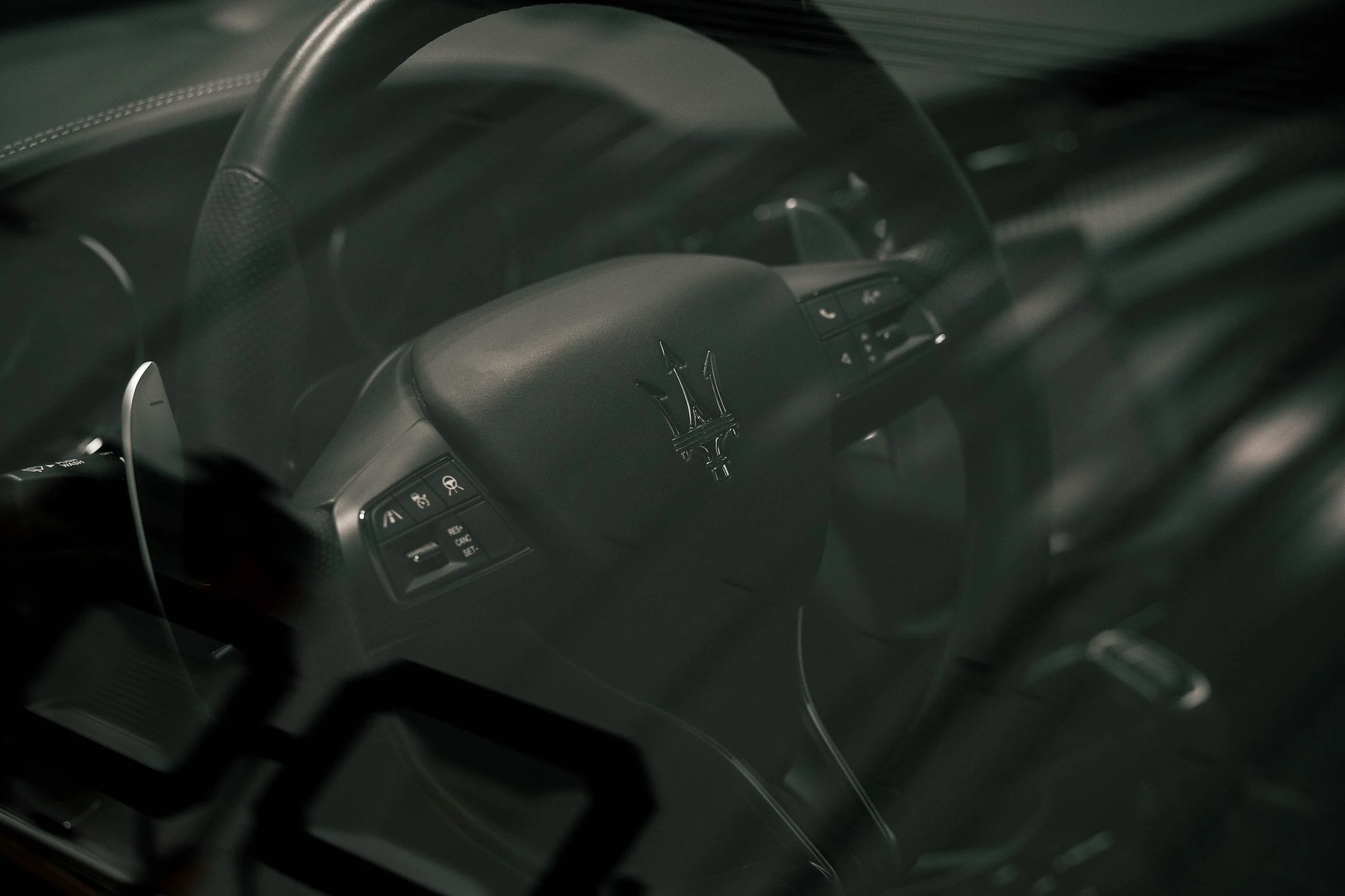 Luxury automotive interior photography showing a Maserati steering wheel and trident badge through the window in Bridgeville, PA