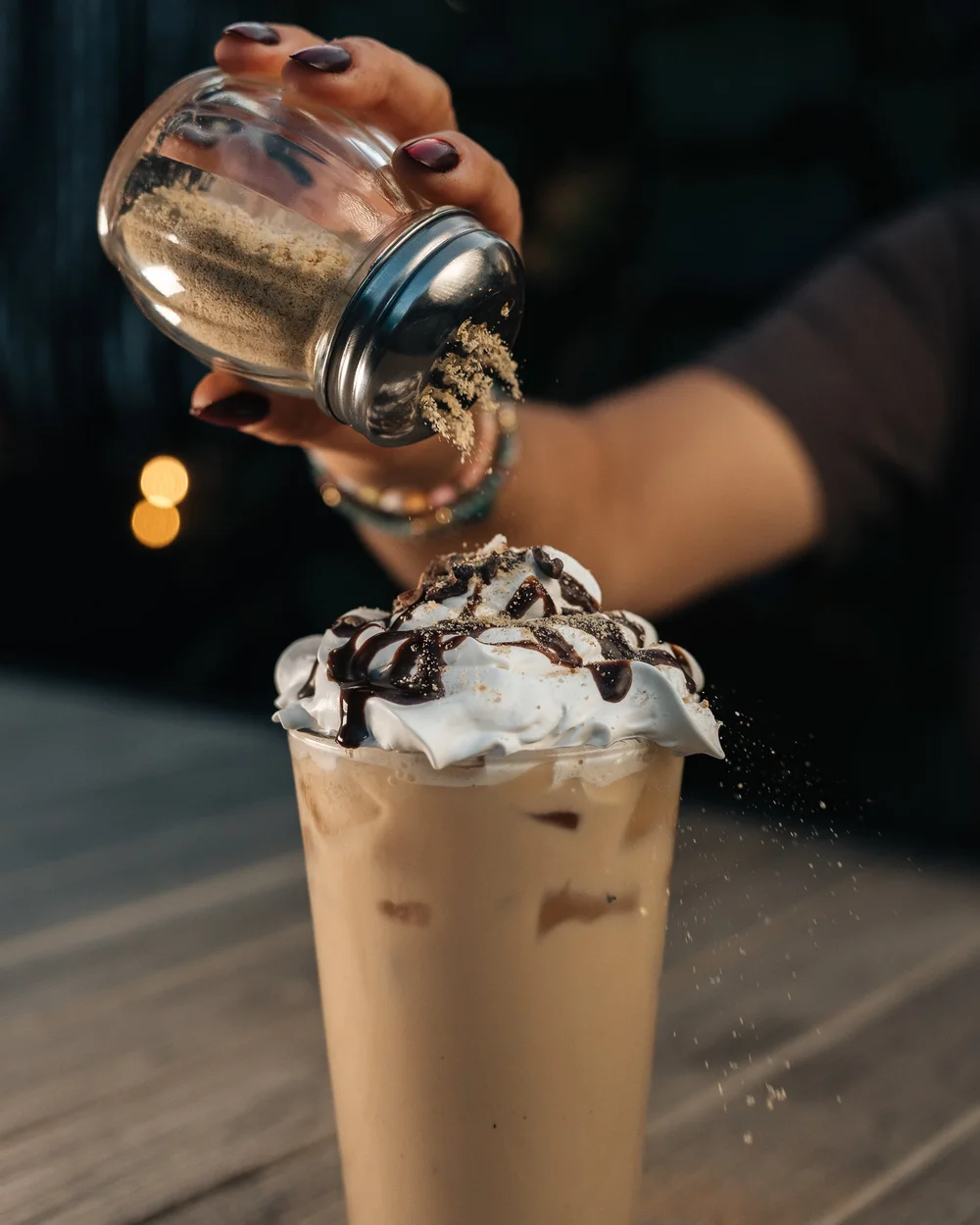 Iced coffee with whipped cream and chocolate drizzle being dusted with spice, Pittsburgh drink photography by Ian Jones.