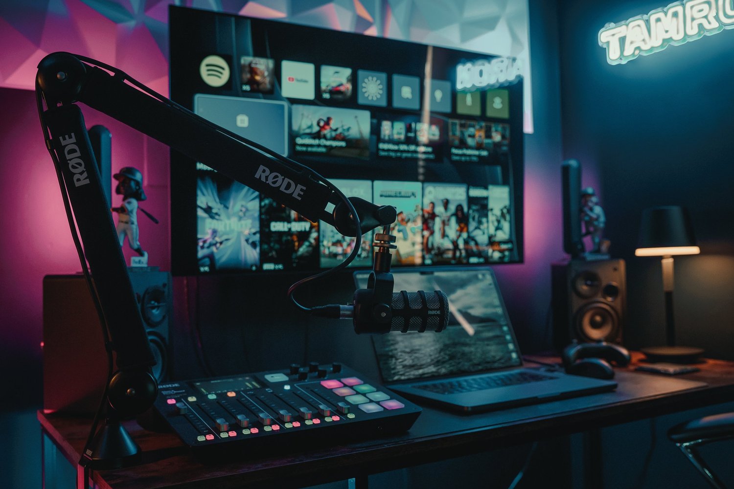 Pittsburgh studio desk setup with RODE microphone, RODECaster Pro, MacBook, monitors, RGB lighting, and acoustic treatment