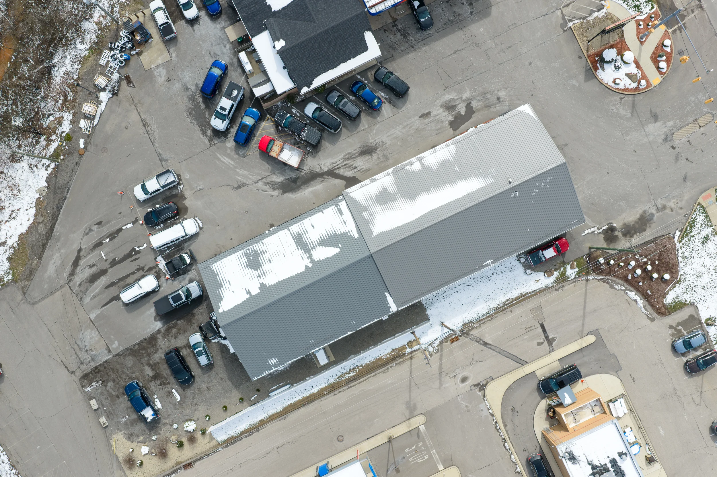 Top-down Pittsburgh drone photography of a commercial building rooftop, parking lot, and surrounding property for real estate and business documentation.