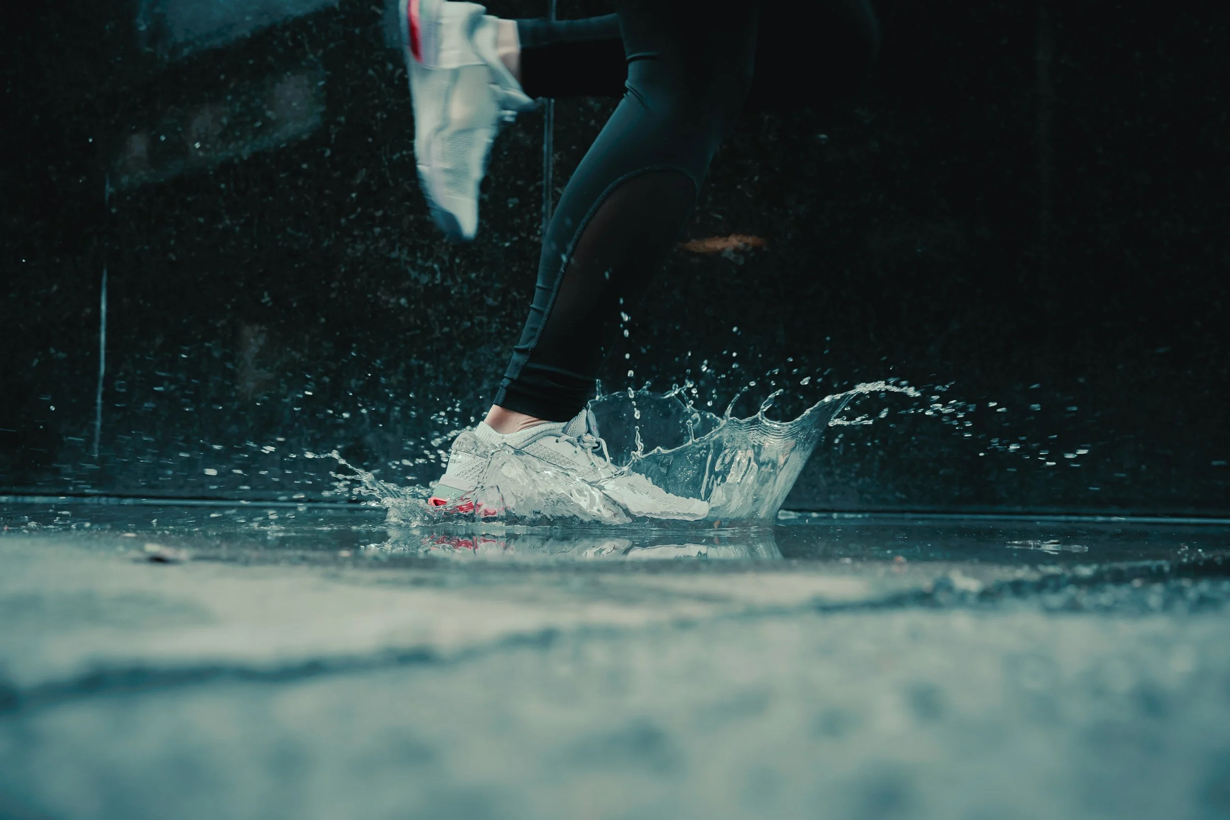 Cinematic lifestyle photography of Nike running shoes splashing through water, captured by Ian Jones in Pittsburgh for dynamic product marketing visuals.