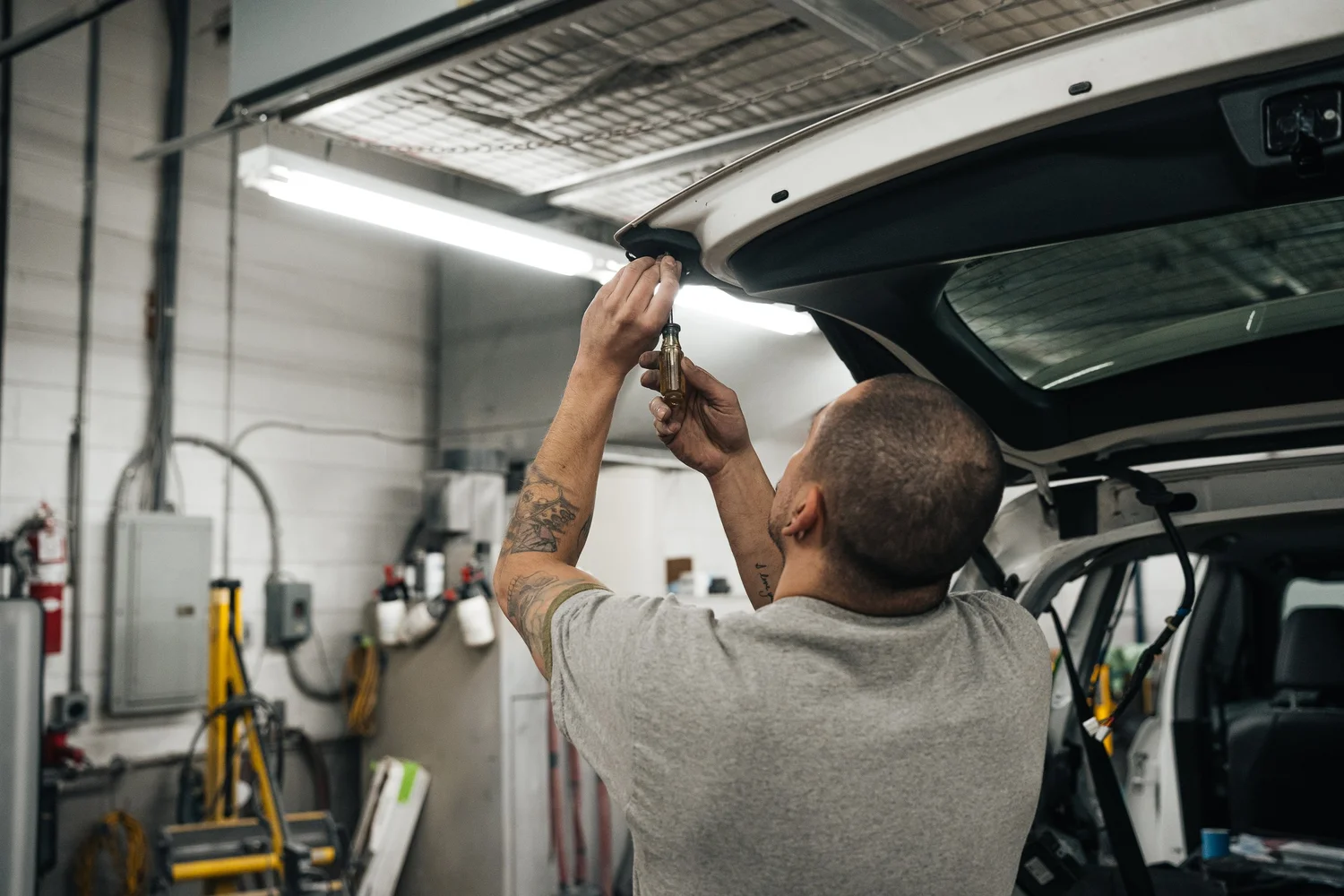 Commercial and industrial photography of an auto body technician working on a vehicle hatchback inside a repair shop by Pittsburgh photographer Ian Jones of ISJDESIGNS