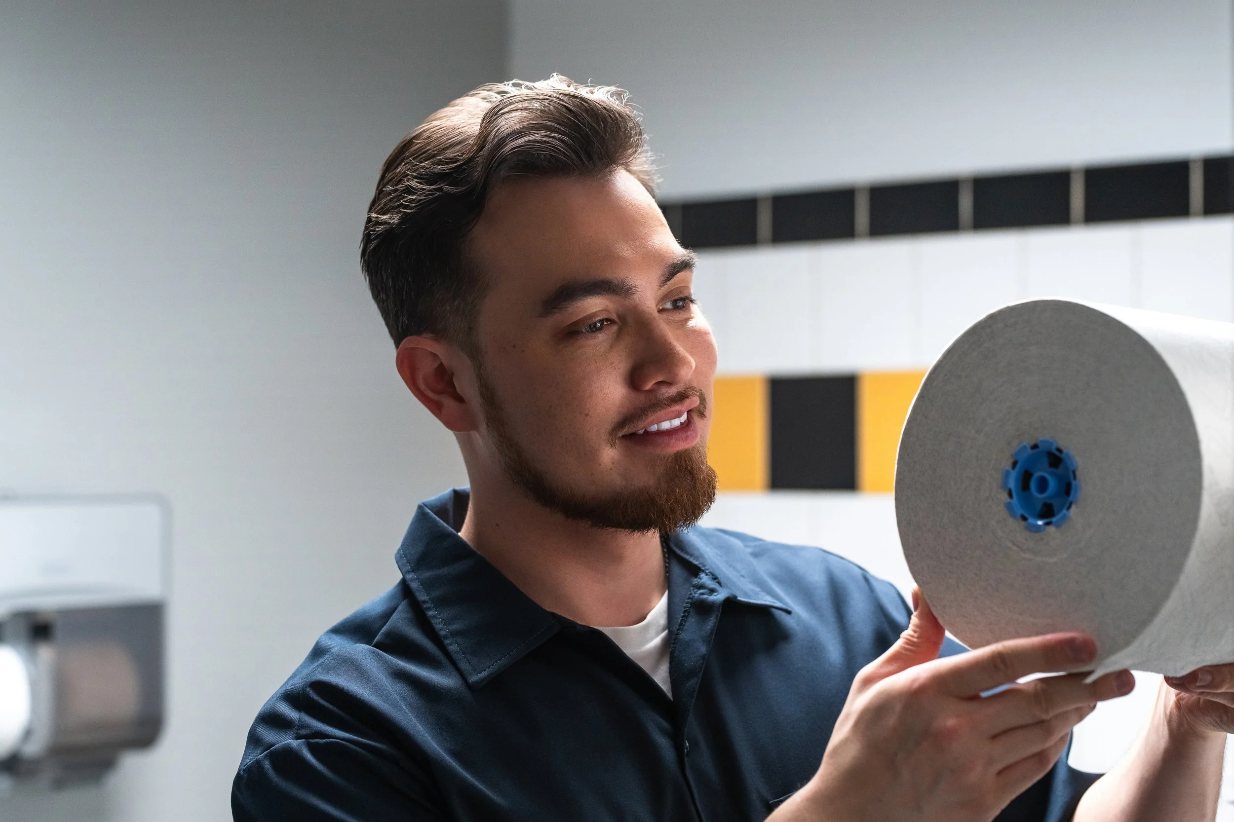Pittsburgh commercial photographer capturing a facility worker holding a large paper towel roll in a commercial restroom setting