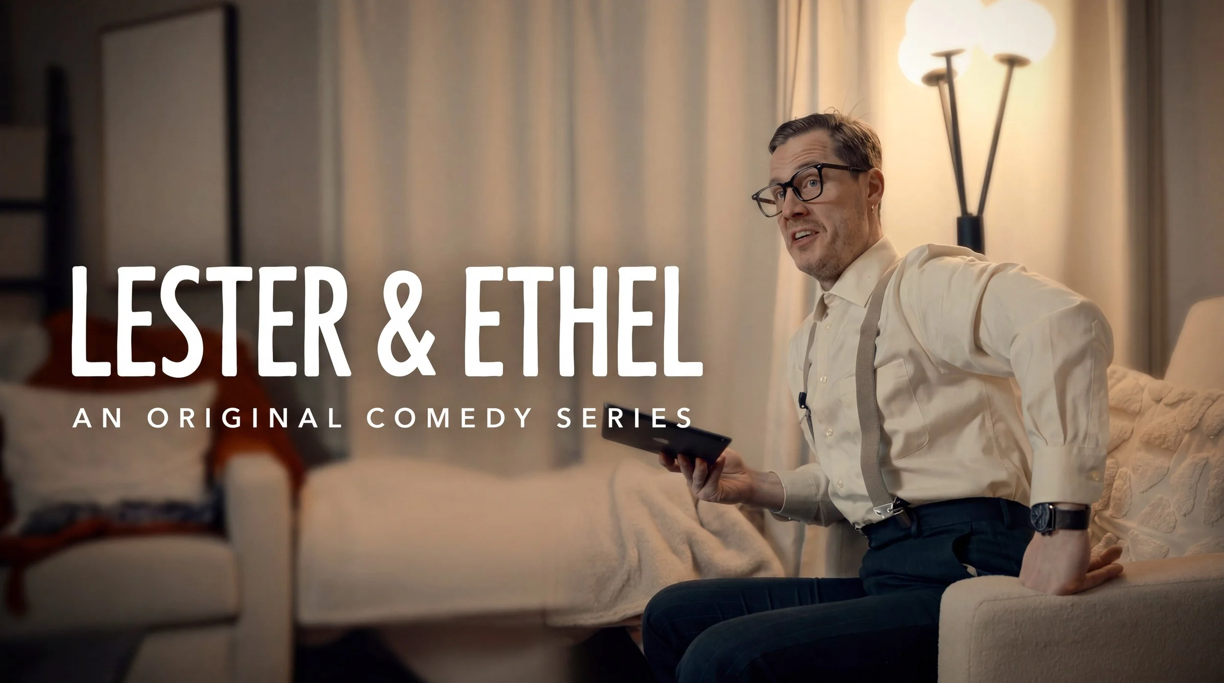 Lester & Ethel — an original retro comedy series created by Ian Jones. A man in glasses and suspenders sits in a warmly lit living room holding a tablet, with the series title in bold white text to his left.