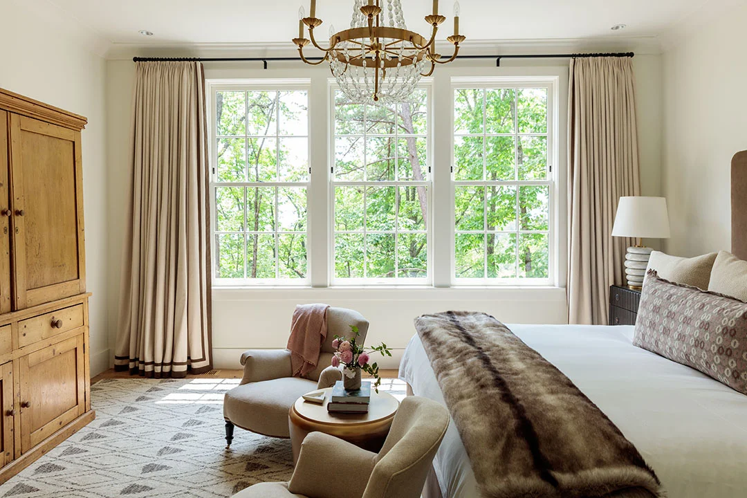 Photo by The Ingalls Master bedroom of a private residence on the rental program with mountain views, antique case pieces and upholstery, Frette bedding and Visual Comfort lighting.