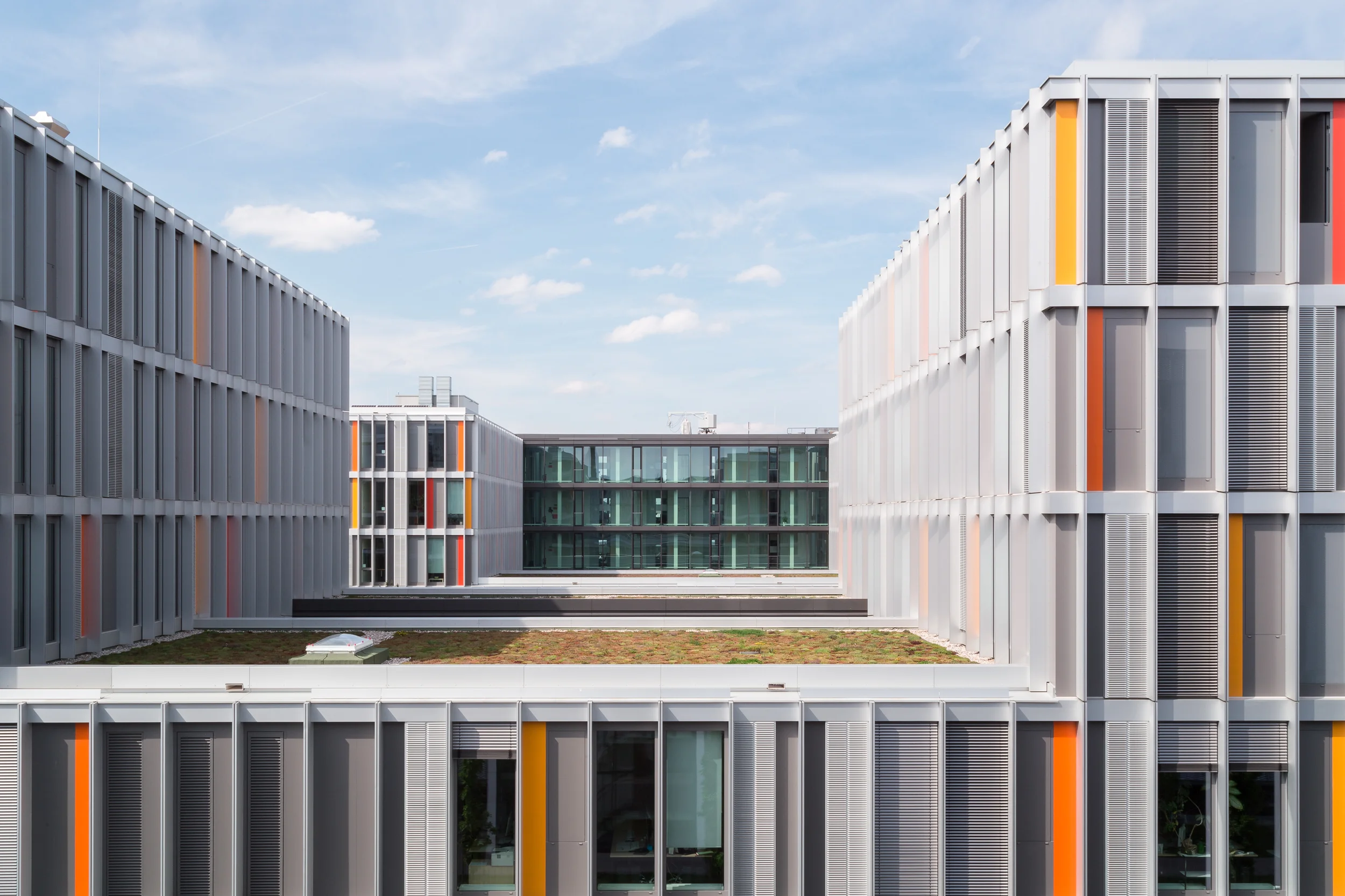 Die Fassade ist mit farbigen Metalllamellen vertikal gegliedert und erinnert an einen Strichcode, der wiederum auf die Arbeit der Nutzer verweist.
