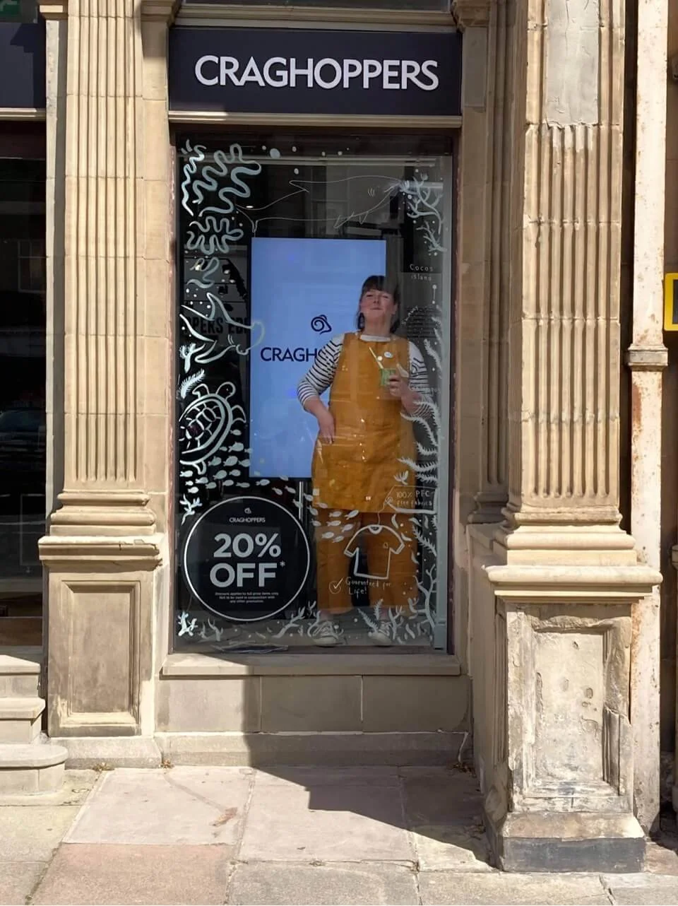 Katie Chappell of Illustrated Live painting a live window illustration for Craghoppers on Edinburgh's George Street, featuring hand-drawn marine and nature illustrations on the shop front glass