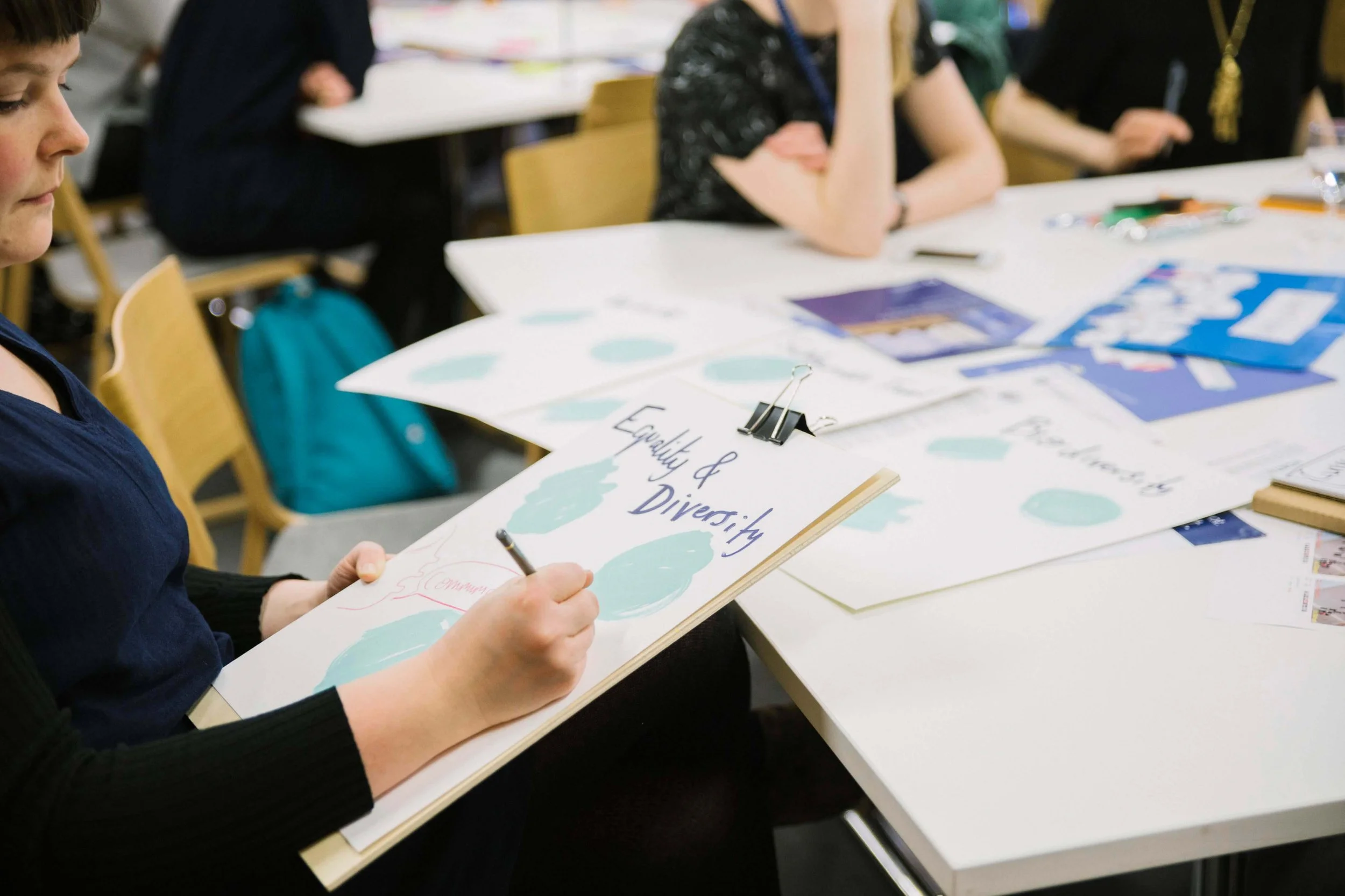 Live illustrator drawing an equality and diversity graphic at a sustainability event at Edinburgh University, with multiple illustrated boards visible across the table