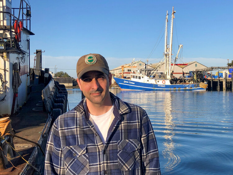 Scott Fosmark at Moss Landing with the Queen Corinne in the background. Photo courtesy of Peter Adame at Lusamerica Fish .