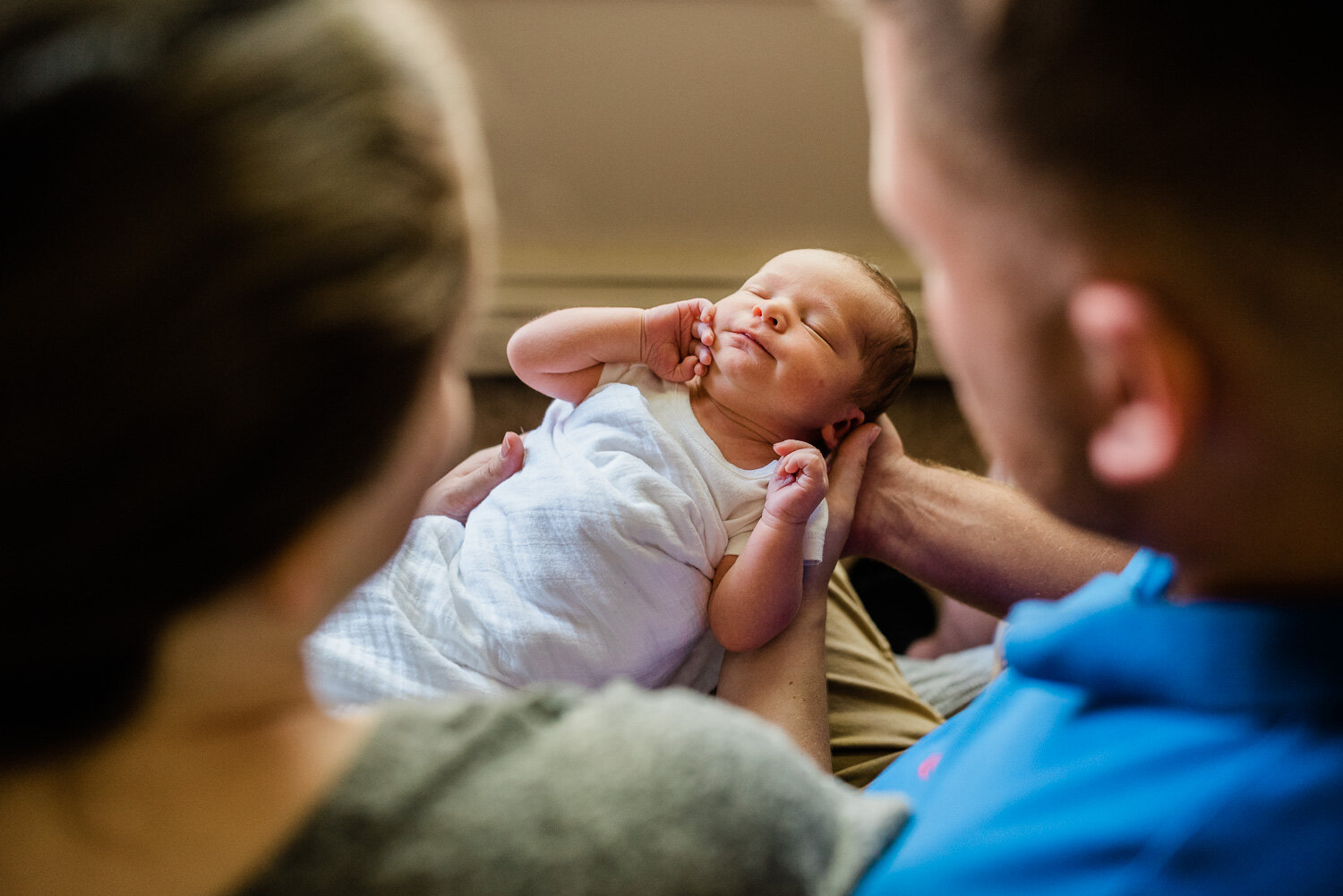 lifestyle newborn photographer in Fort Drum, NY - baby being held by mom and dad.jpg