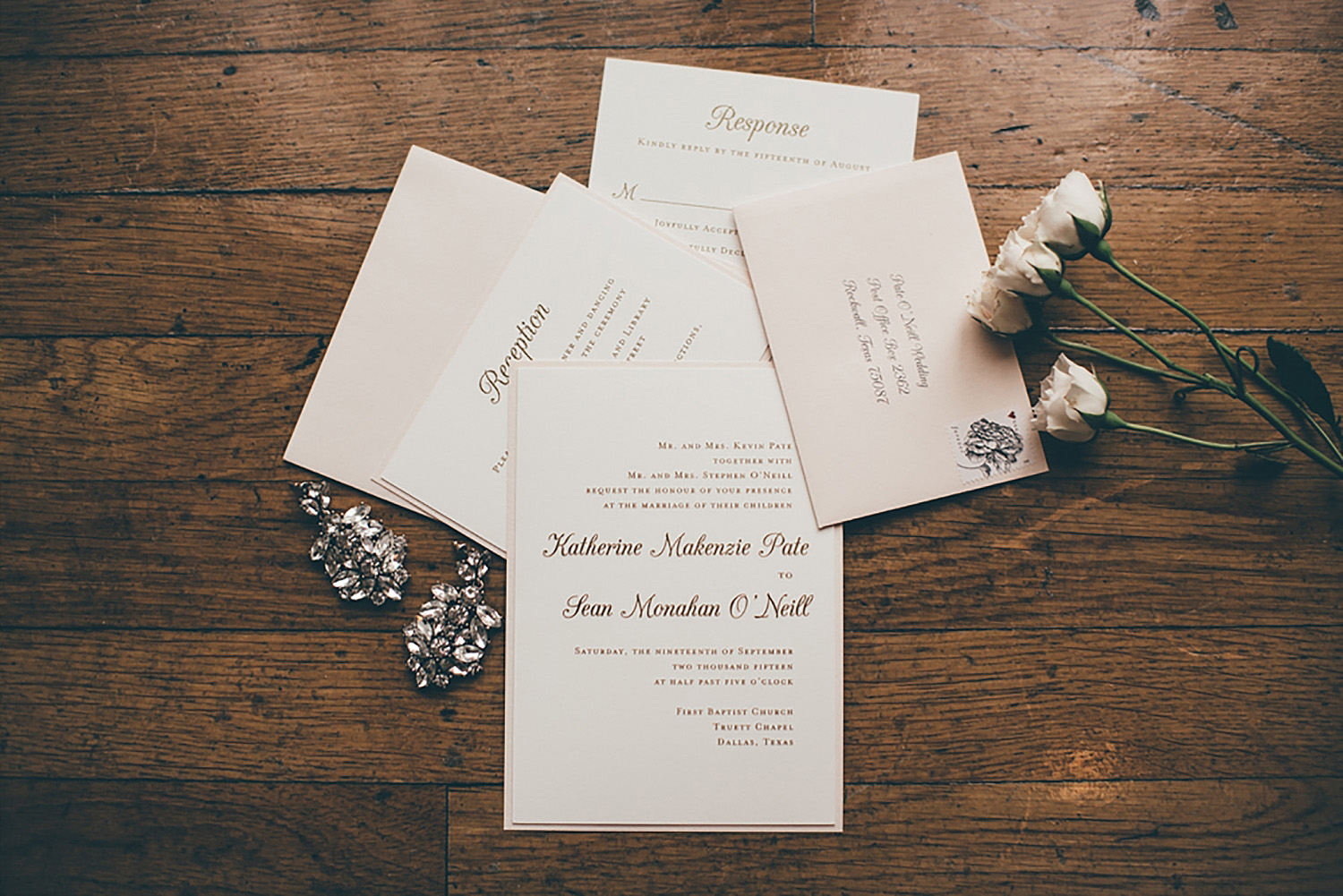 Dallas Scottish Rite Library and Museum wedding invitations with gold writing and white flowers on wood floor
