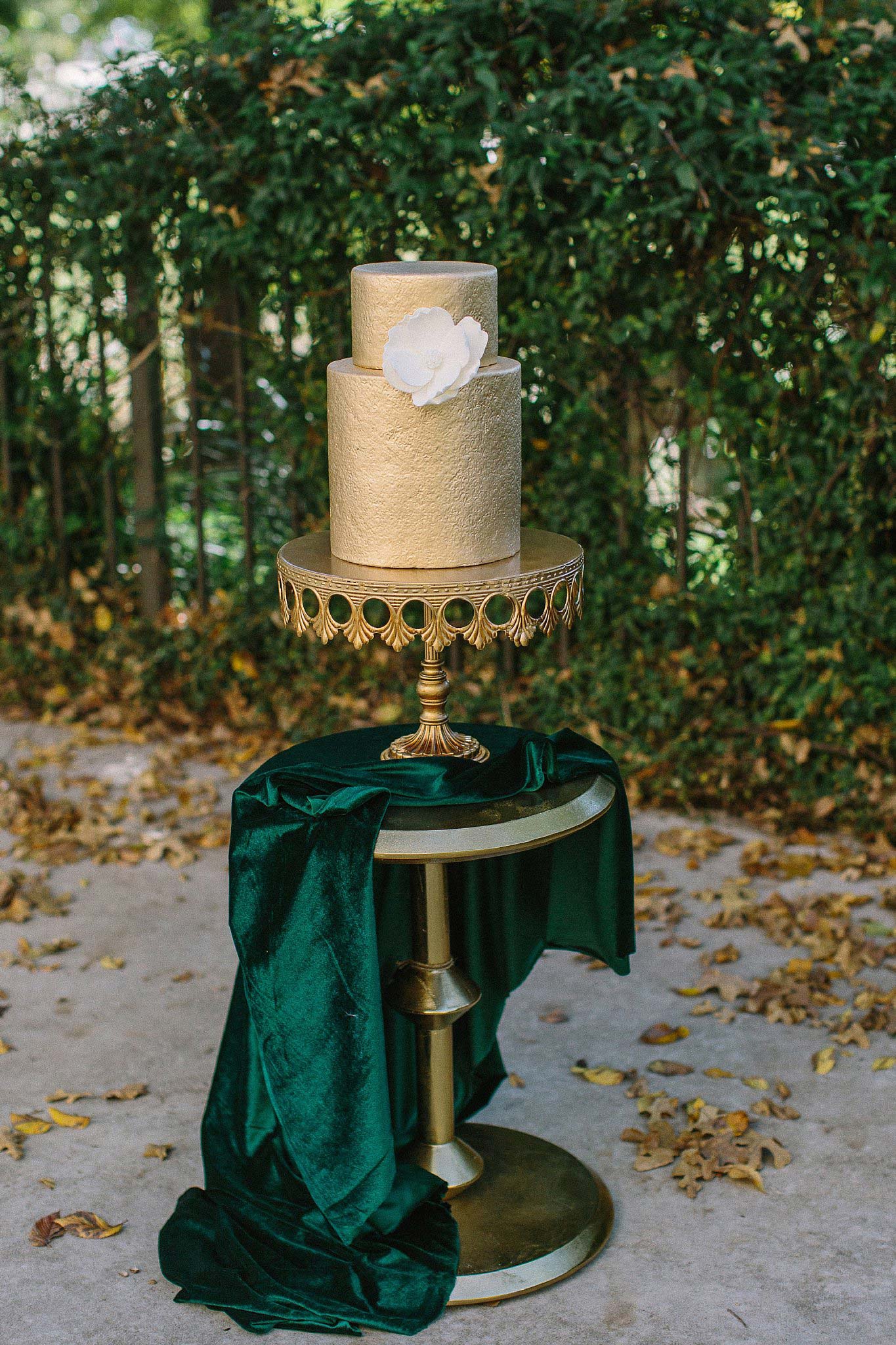 aristide mansfield wedding gold wedding cake with white magnolia on green velvet fabric