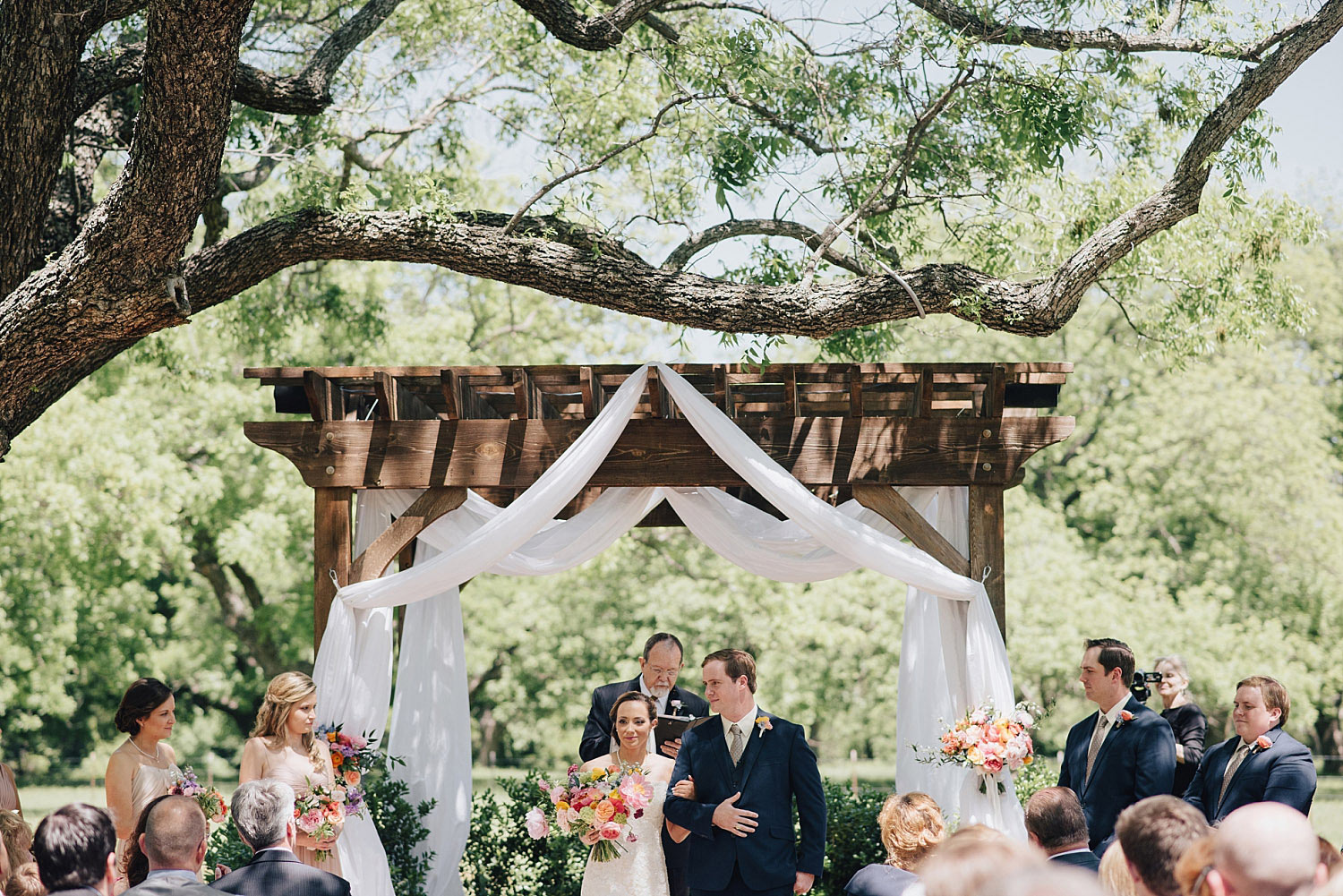 The Orchard Azle wedding ceremony at wood trellis with white fabric