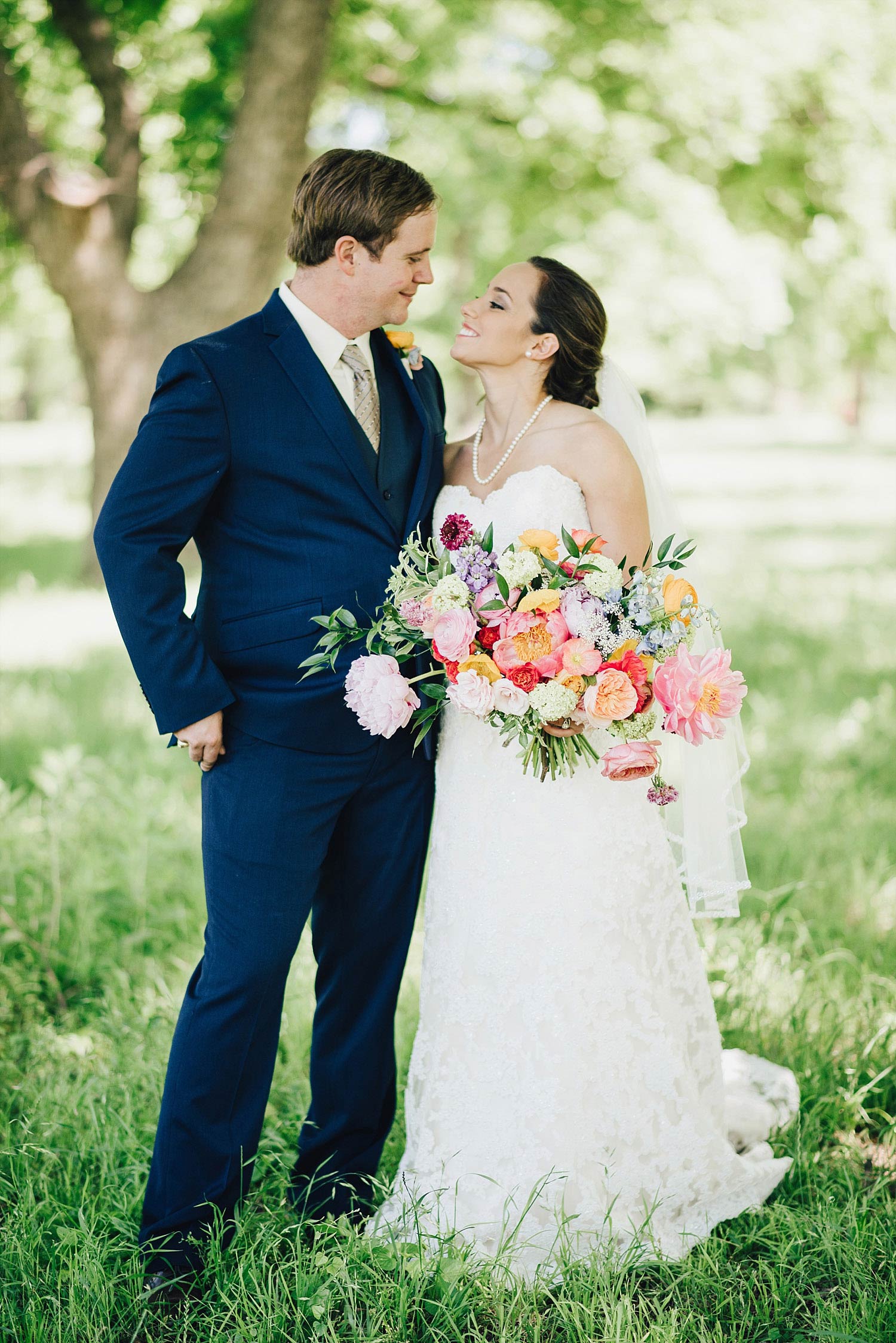 The Orchard Azle wedding bride with colorful bridal bouquet kissing groom