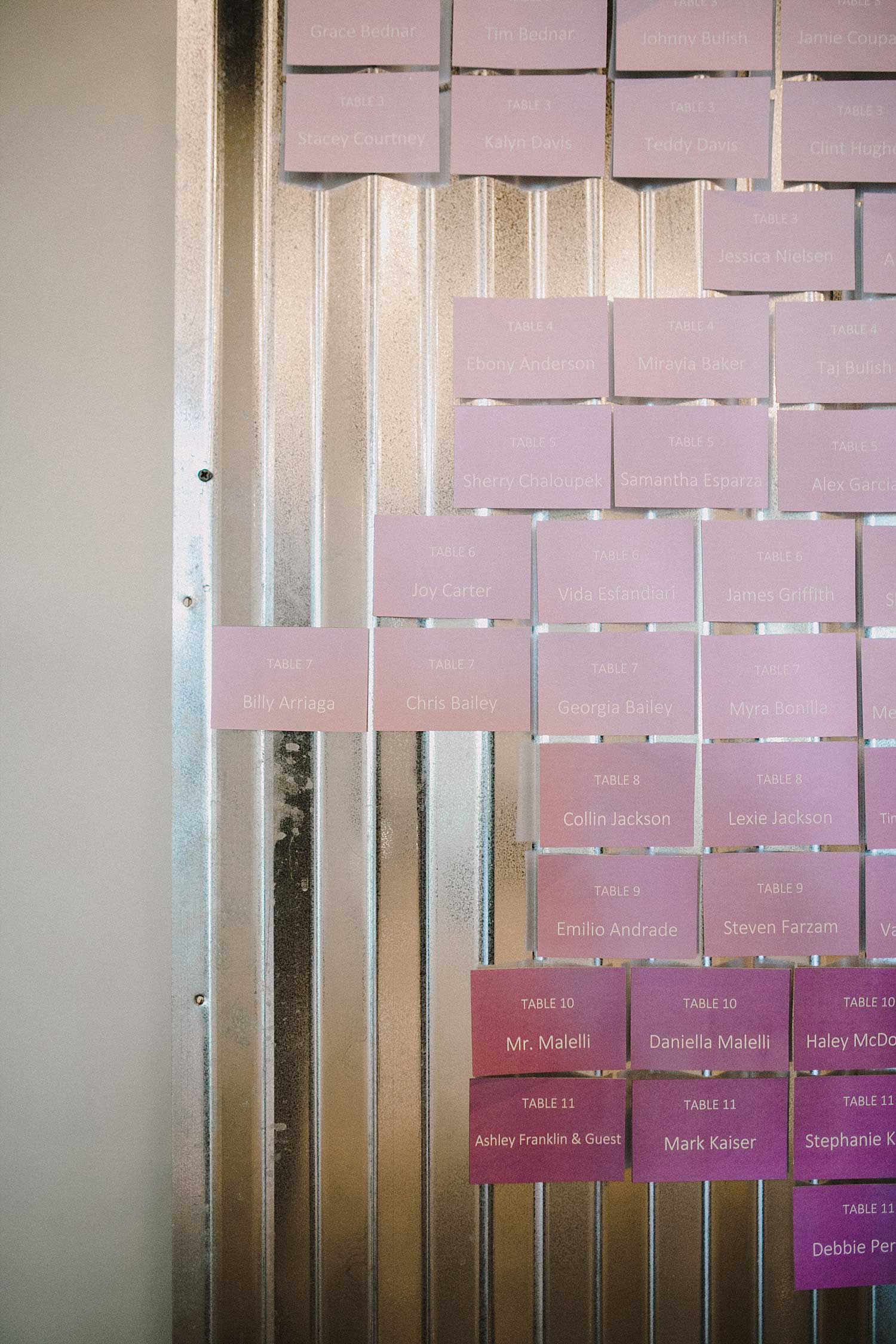 Lavender ombre escort cards on a galvanized metal wall